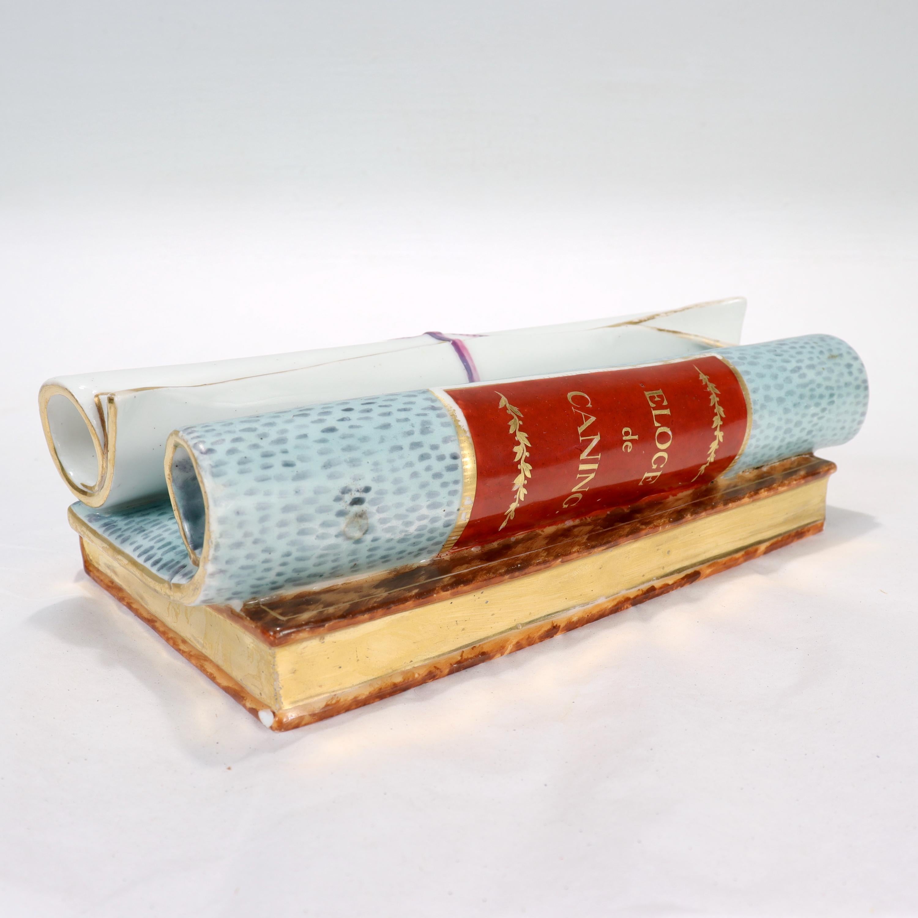 A fine antique French porcelain Trompe L'oeil paperweight or sculpture. 

In the form of a book with 2 scrolls stacked on top of it. 

The book's spine reads 'Biron' (likely the memoir of Armand Louis de Gontaut), while one of the scrolls is