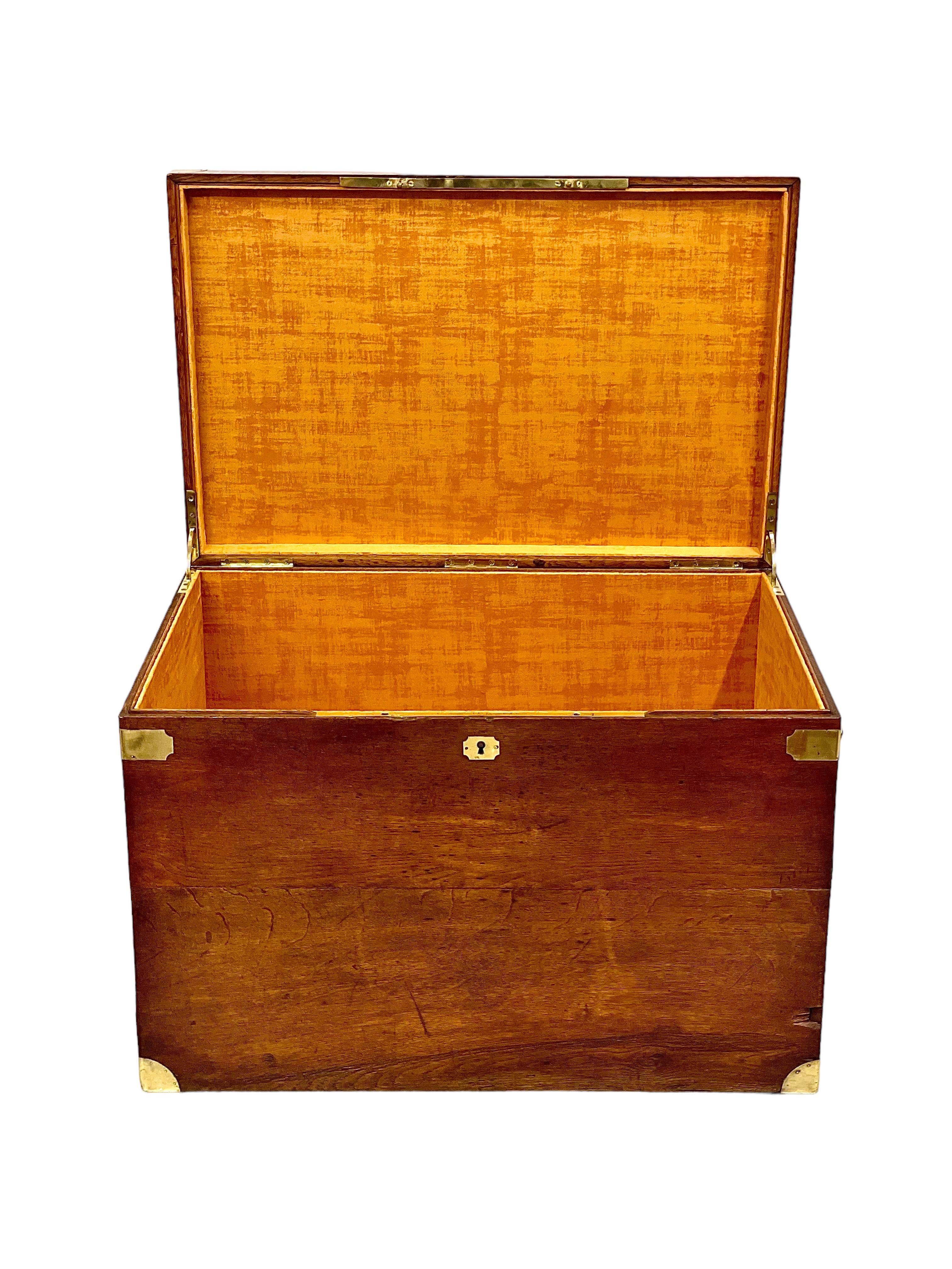A sturdy and practical antique French storage trunk, made from oak, with brass fixings and bronze side handles, dating from the end of the 19th century. Inlaid on the top is a brass plate sporting a coat of arms surmounted by a heraldic helmet and