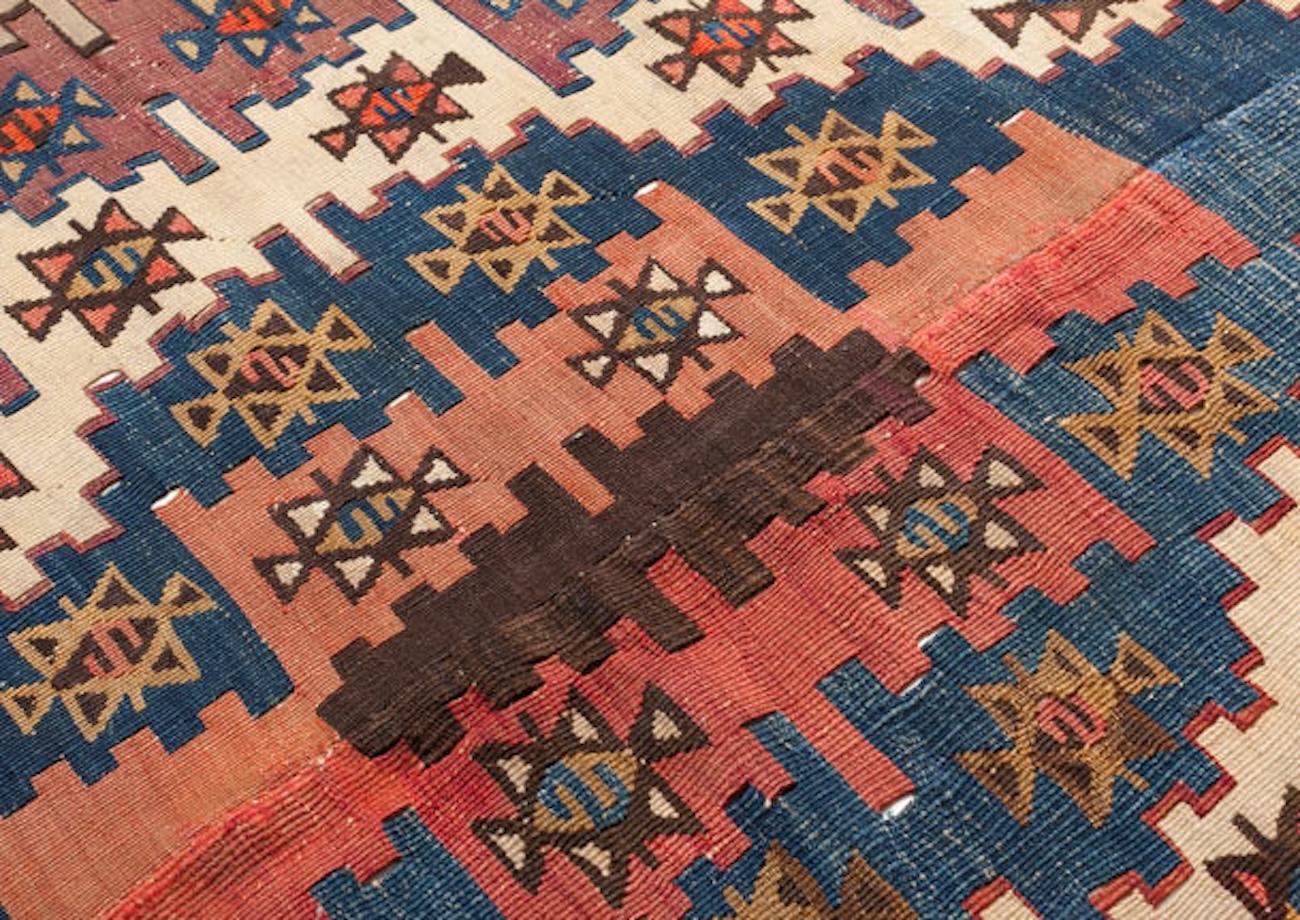 This is a traditionally handwoven kilim from Türkiye, square-like, measuring 150 cm x 166 cm and made from 100% wool.

Design and Features;
This kilim showcases a distinctive Parmaklı (meaning “fingered”) motif, which resembles the interlaced