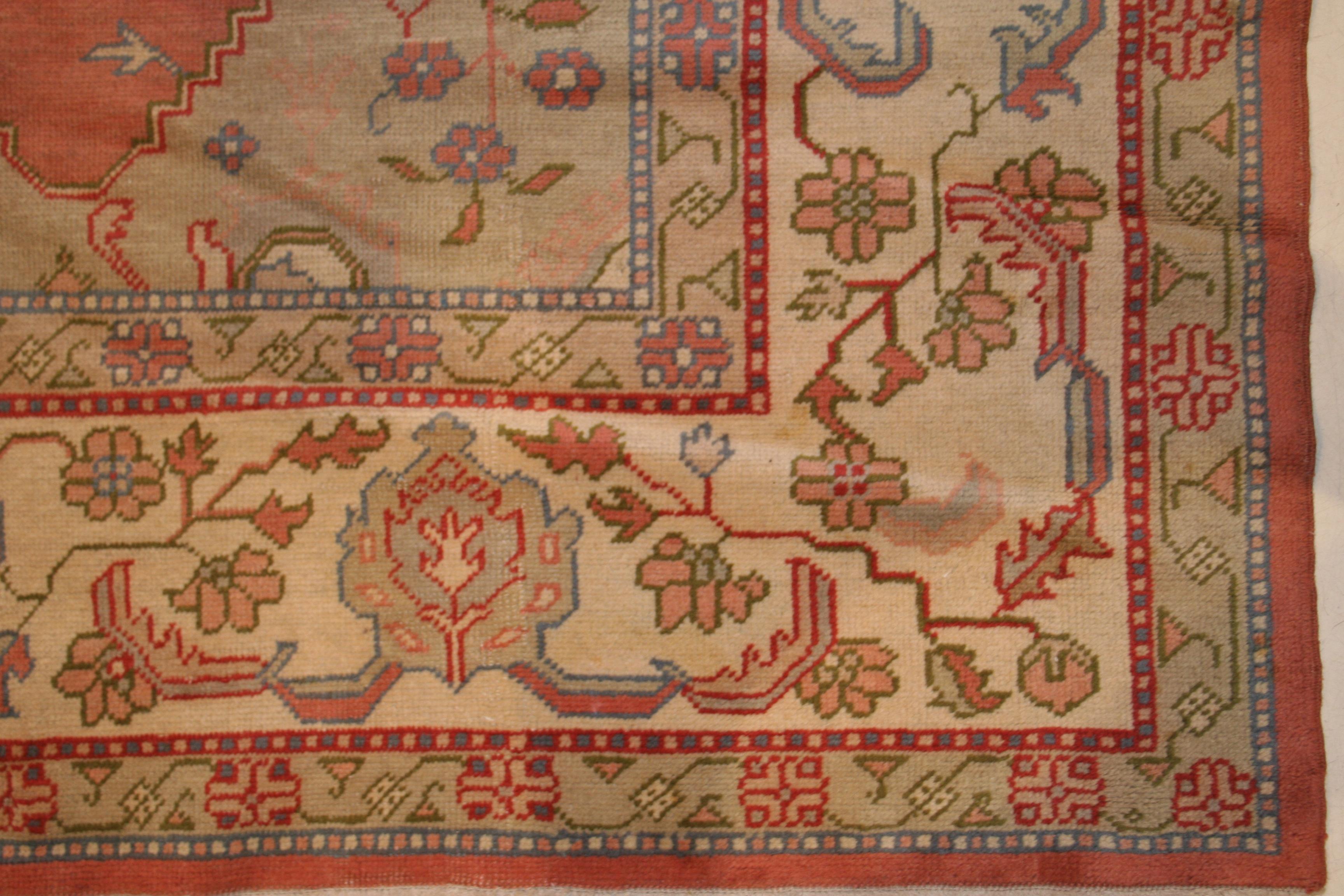 La palette douce de cet ancien Oushak d'Anatolie est caractéristique de ce groupe de tapis de la fin de la période ottomane. Le fond rose saumon pâle est agrémenté d'un médaillon central ogival ivoire et entouré d'écoinçons vert céladon. La bordure