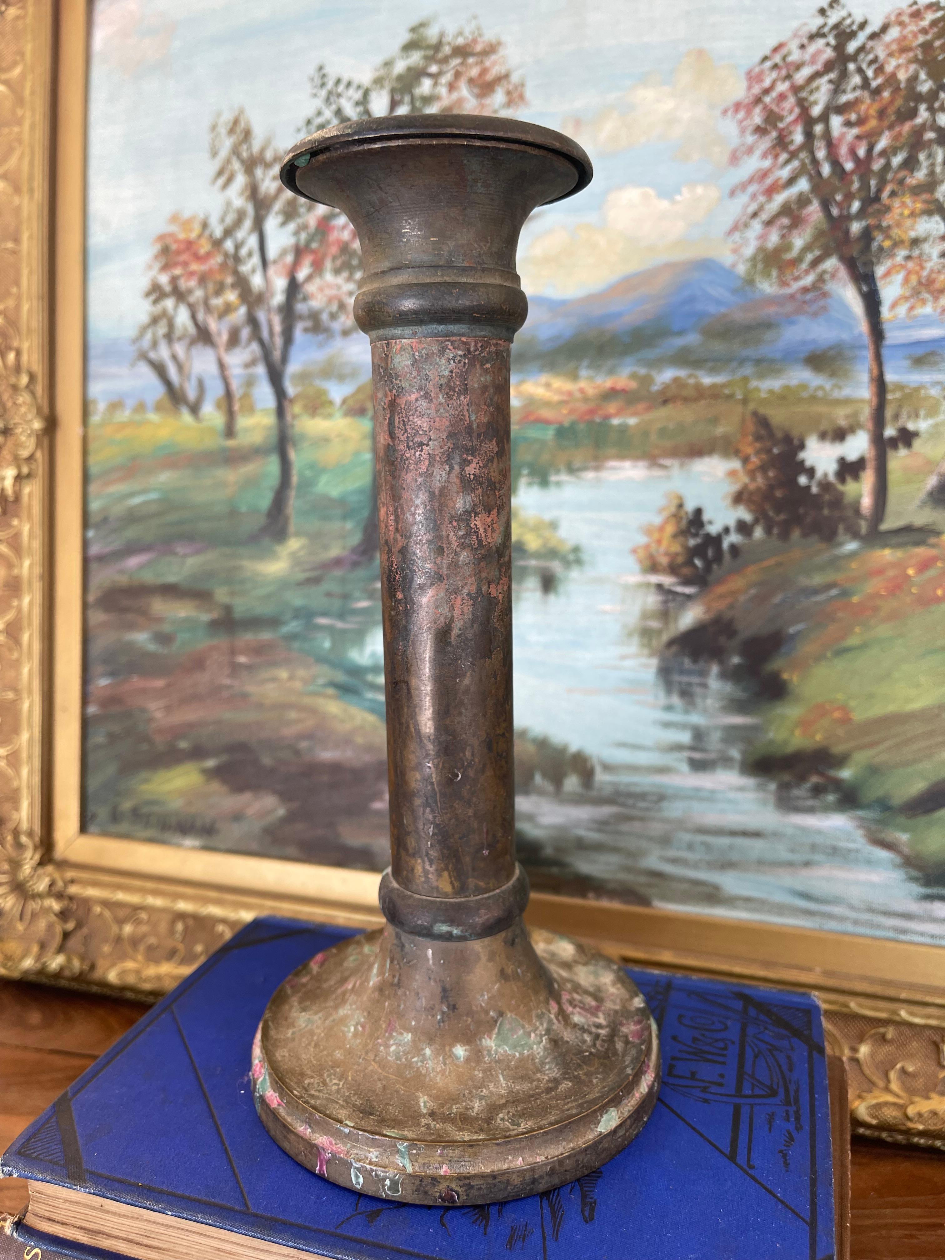  Likely Early 20th-century solid brass toned candlestick holder featuring a flared lip and wide, rounded base.The surface has developed a rich, timeworn patina, with visible wax residue along the base evidence of long use. Underside shows oxidation