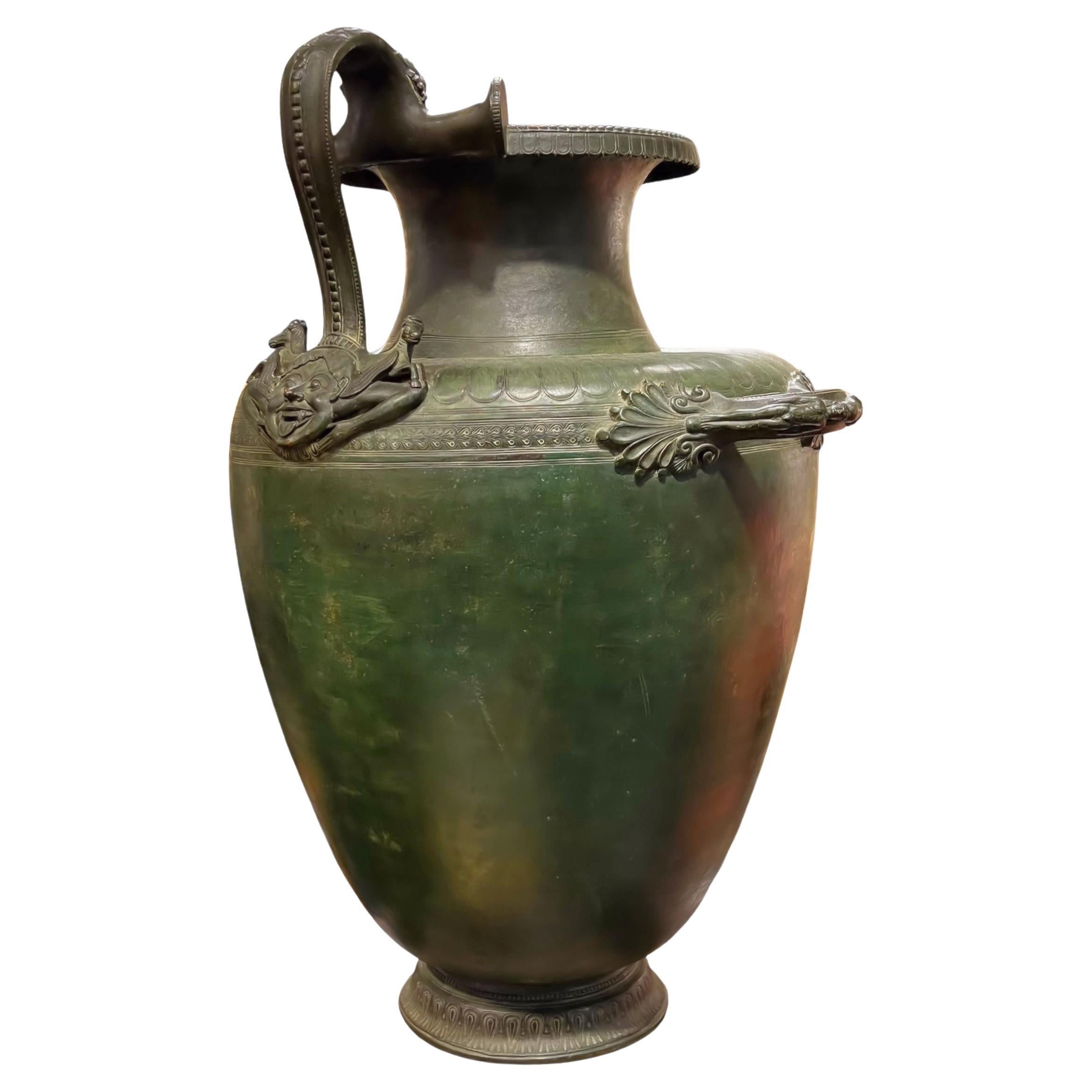 Our antique Grand Tour bronze hydria water jar after the original Greek design, circa 5th century BC, has a verdigris green patina and is finely cast with a winged laughing mask and hippocamps above and handles to the sides.  Possibly from the