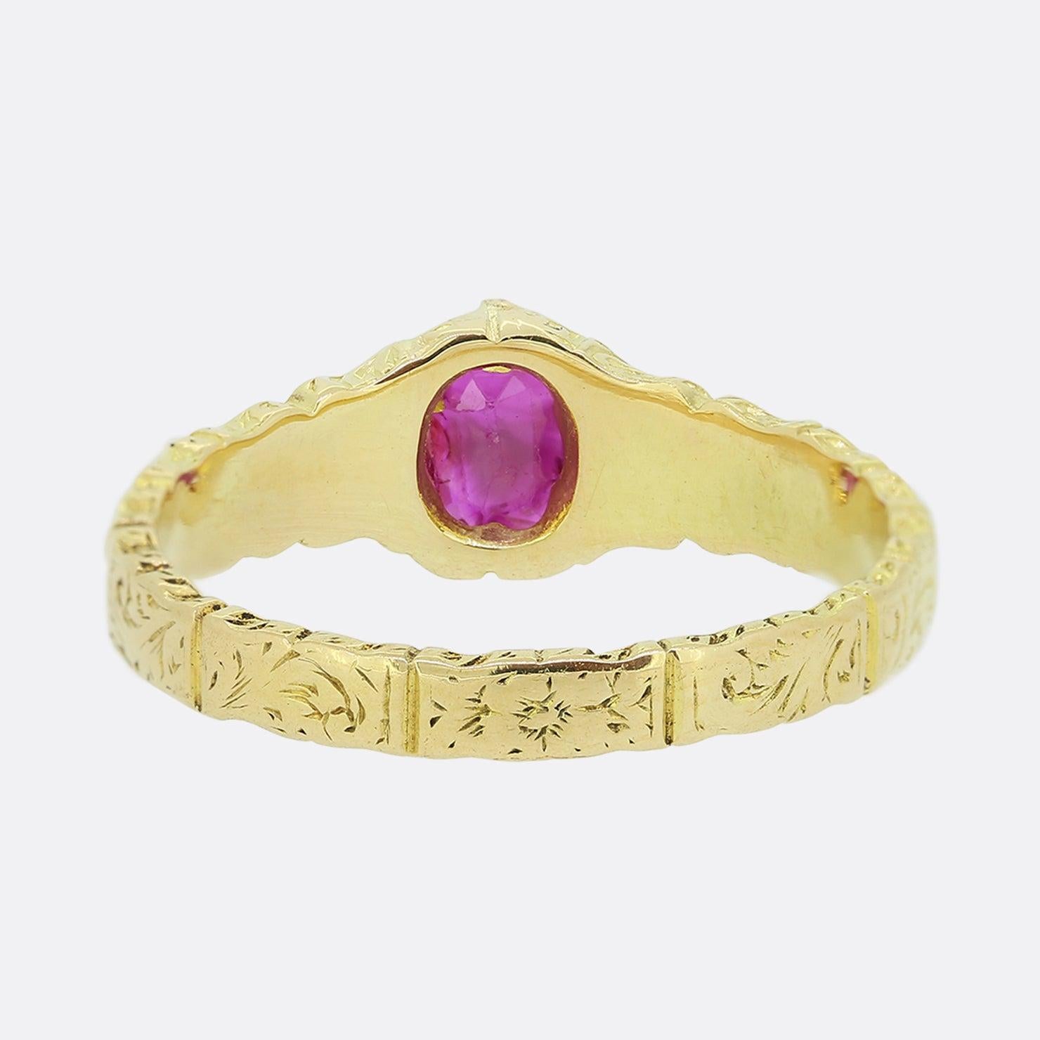 This is an antique 18ct yellow gold ruby ring. The band of the ring features a delicately hand engraved pattern which goes the whole way around the band. The ruby is a mid red hue with a slight pink undertone and has a couple of noticeable