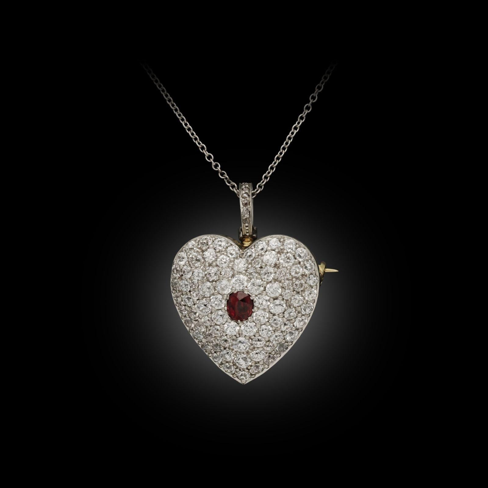 A beautiful antique diamond and ruby heart brooch/ pendant c.1915, the domed heart finely crafted in platinum and backed with gold centred on a cushion shaped rich red ruby and then pavé set throughout with old cut diamonds with a pierced open