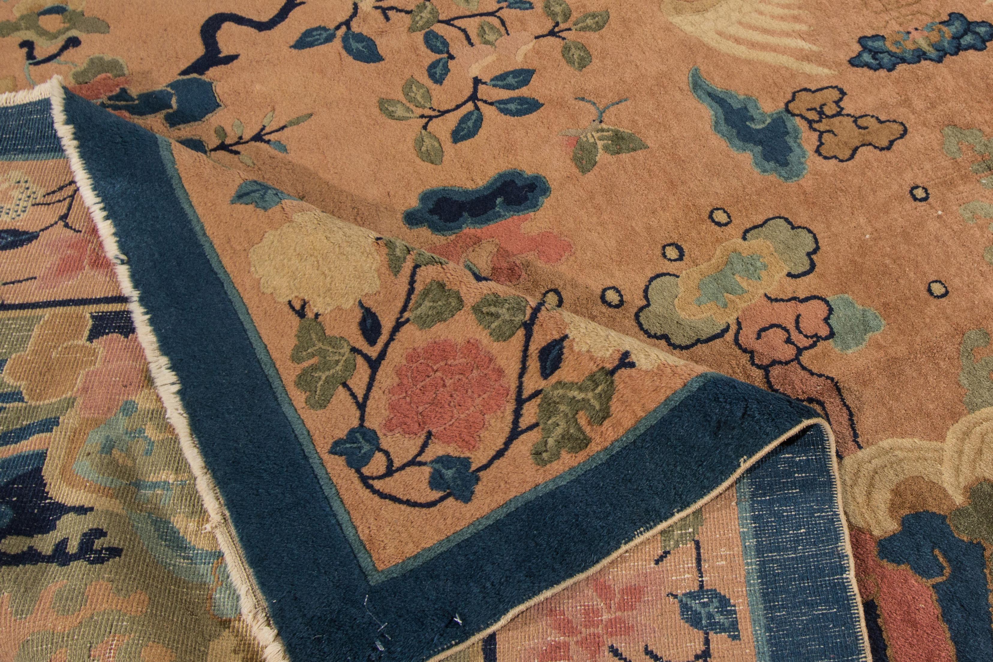 A beautiful hand knotted antique Chinese Peking wool rug with a peach field and multi-color accents in all-over Chinese botanical design. 

This rug measures 9' x 11'9
