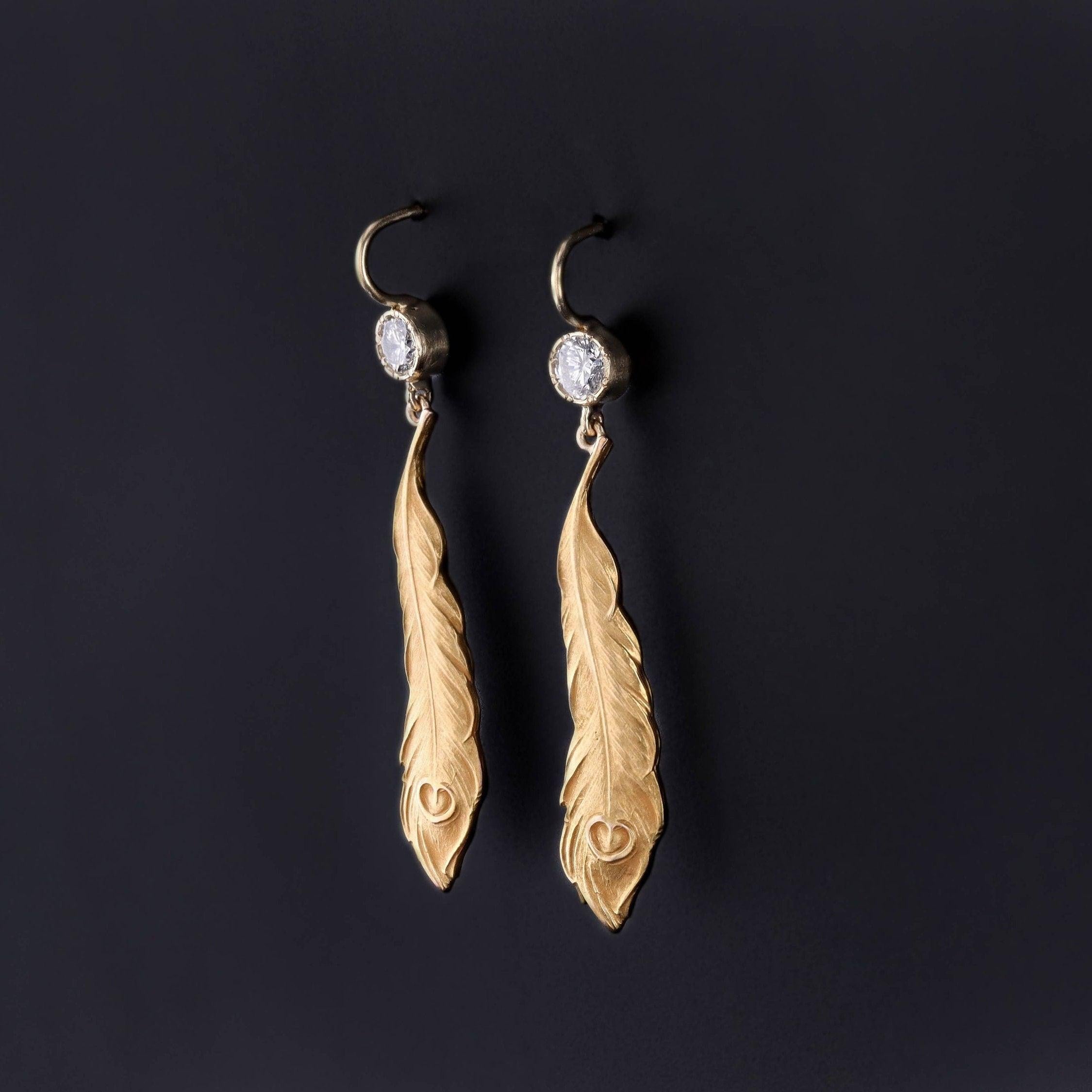 These antique 14k gold earrings feature finely rendered peacock feathers with diamond surmounts. The feathers were originally Art Nouveau era pins (circa 1910) that our jeweler transformed by removing the pin findings and adding gold ear wires and