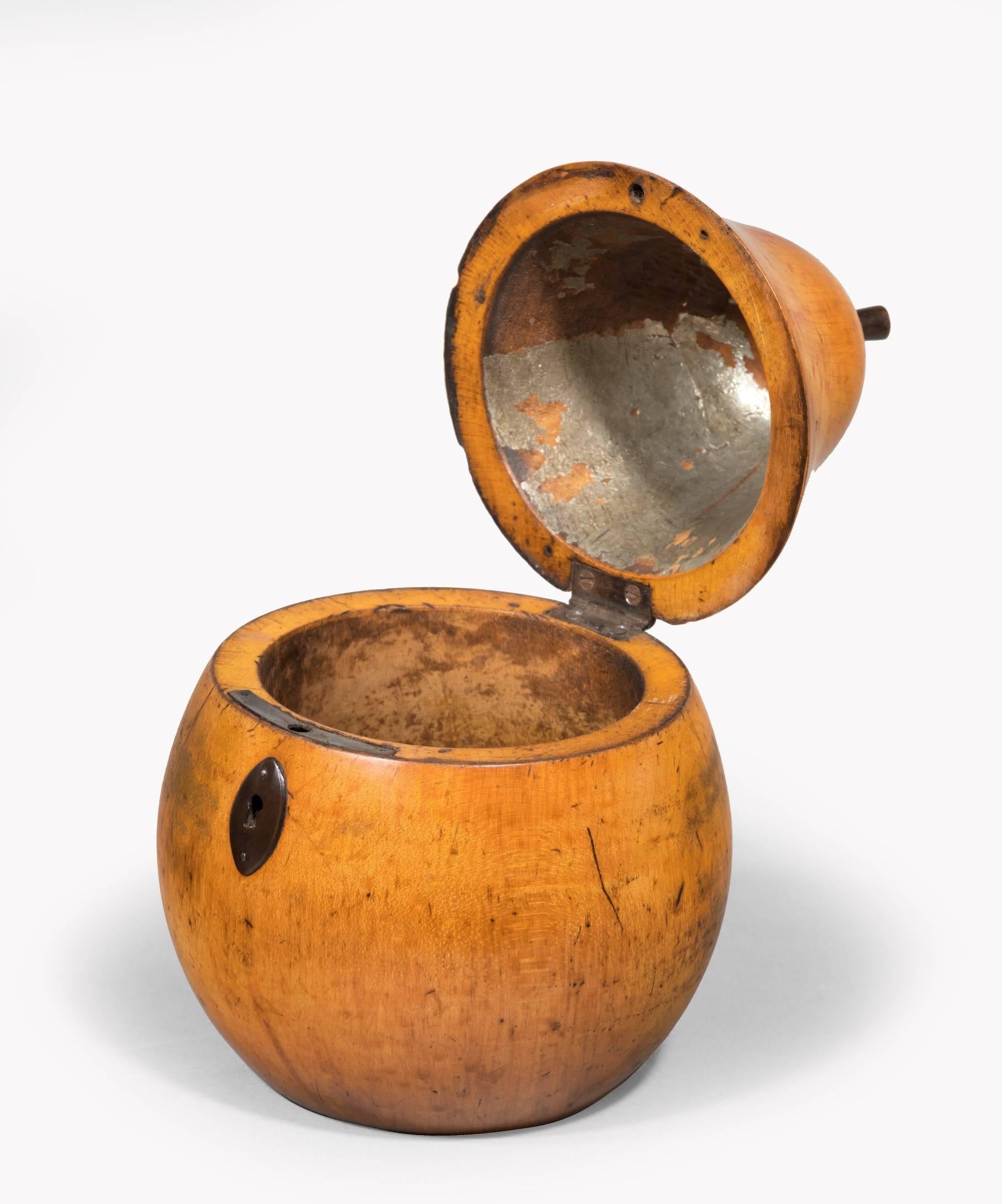 A rare Georgian fruitwood treen tea caddy modelled in the form of a pear; the pear's carved stalk can be used to open the lid which opens to reveal some of the original foil lining; having a steel escutcheon and a good colour.

Fruit tea caddies