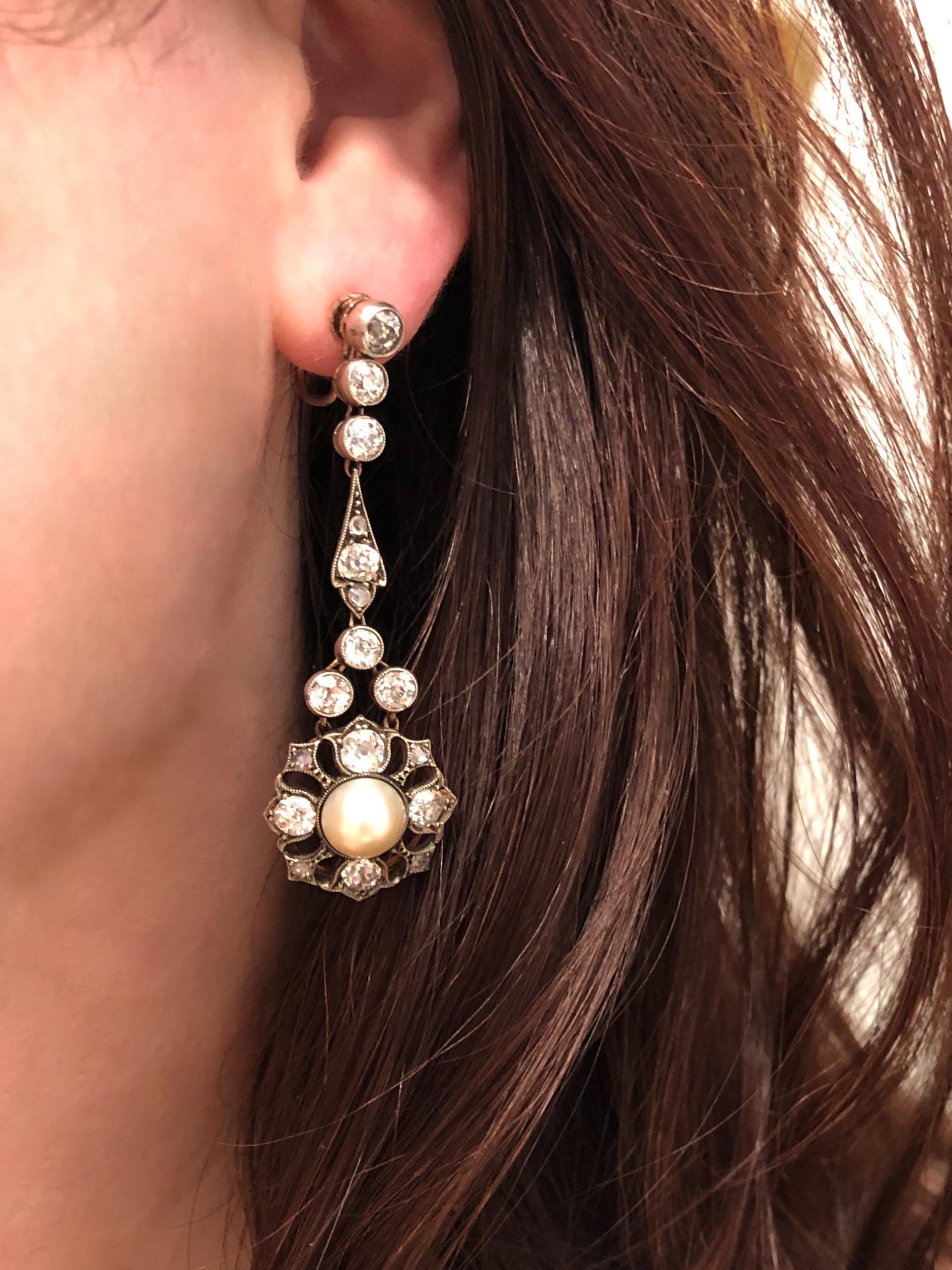 A pair of button pearls is central to a suspended cluster mounted in silver topped yellow gold with old European cut diamonds totaling approximately 4.75 carats. Pearls measure 8 mm. 2-1/4 inch length. Currently with screw fittings for non-pierced