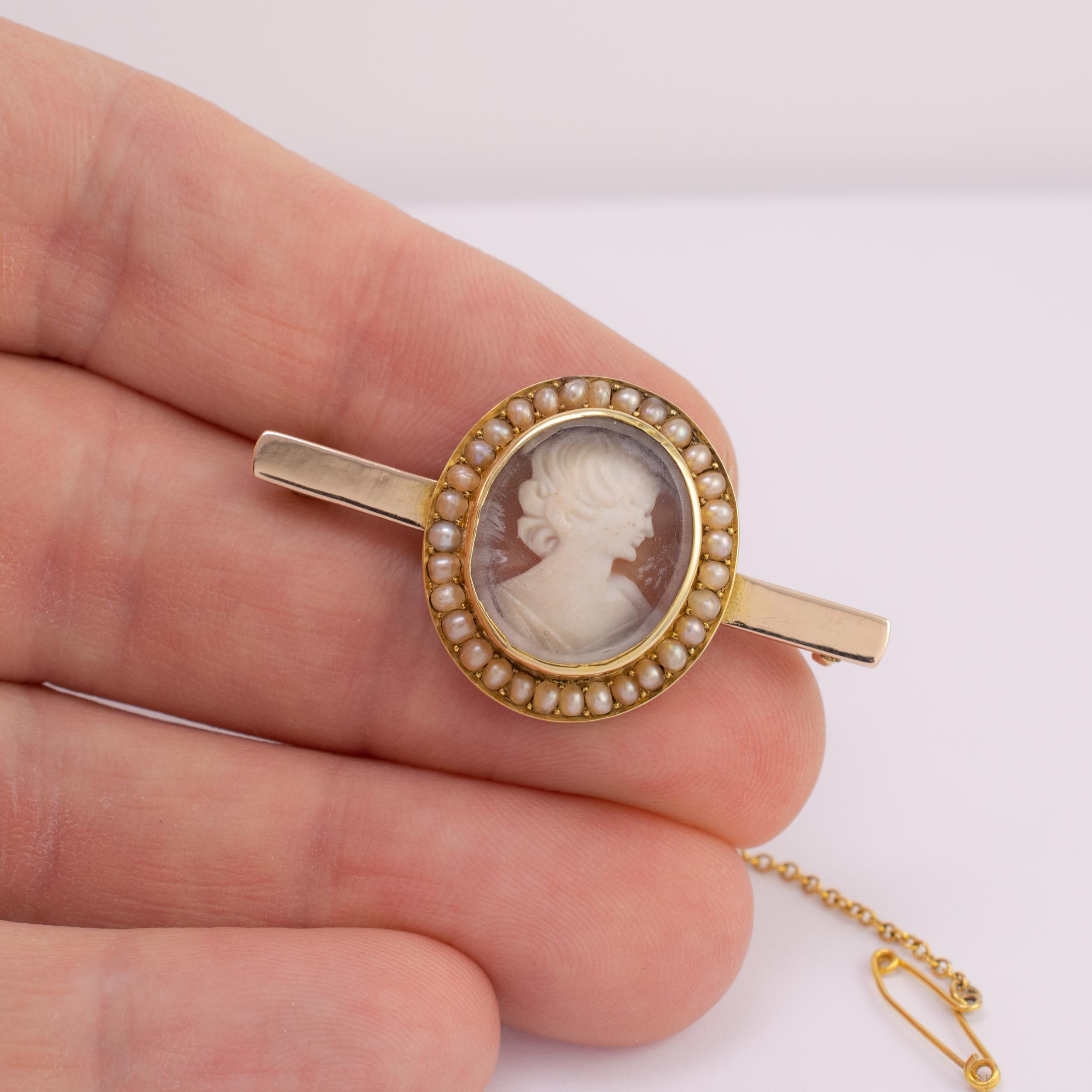 This fine quality antique pearl cameo brooch is crafted in 9 karat gold and dates Circa 1900 Germany.

The brooch displays a center oval gold mount with bezel edge set with female portrait, in relief, carved from shell, encased inside protective