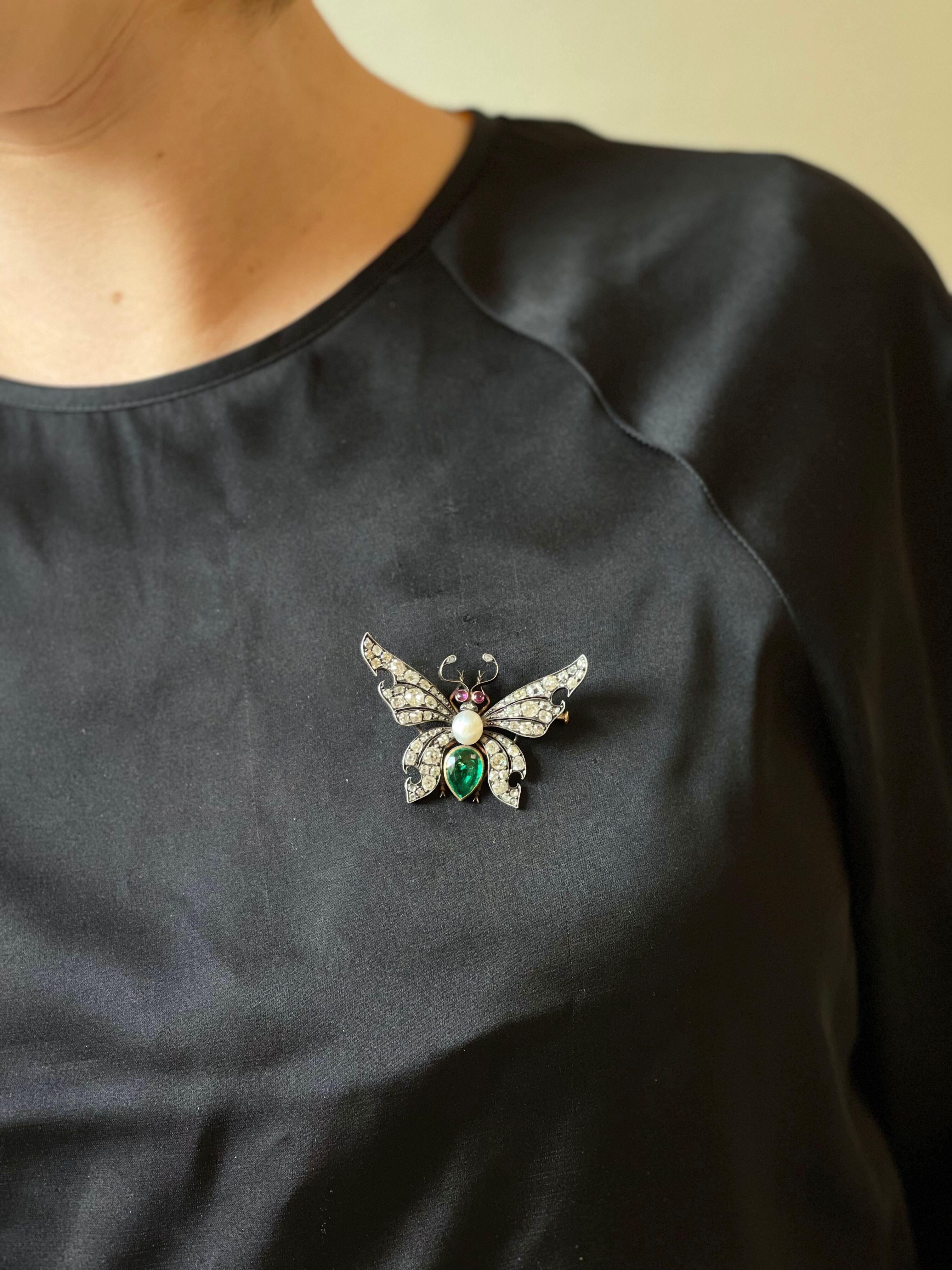Antique 14k gold and silver top butterfly brooch, adorned with 6.8mm x 8mm pearl, pear shaped emerald, ruby eyes and approx. 2.20ctw in old mine cut diamonds. The brooch measures 2