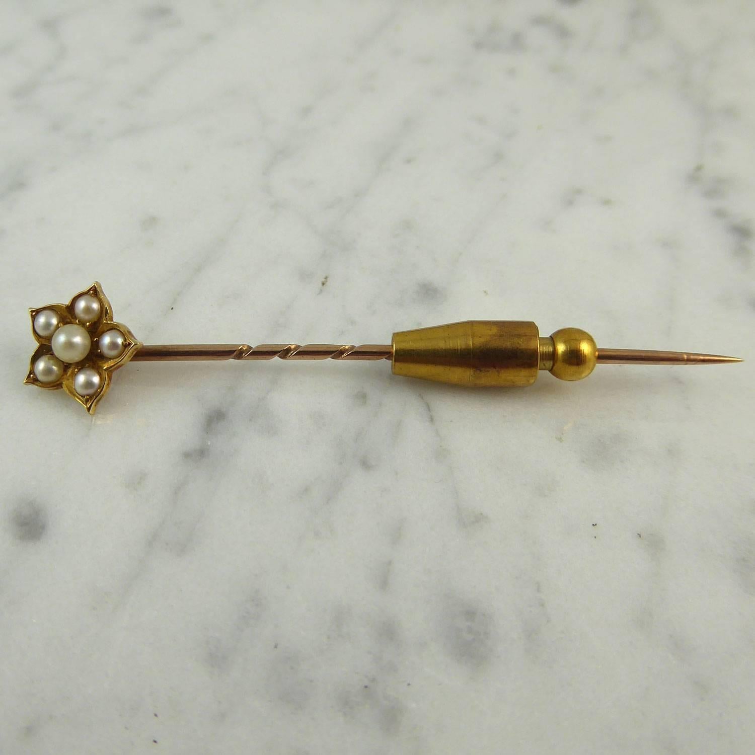 Dating from the late Victorian early Edwardian era, this antique stick pin has been fashioned in a flower style.  Set to the centre with a round white pearl approx. 3.0mm in diameter to a surround of five white pearls each measuring approx. 2.0mm
