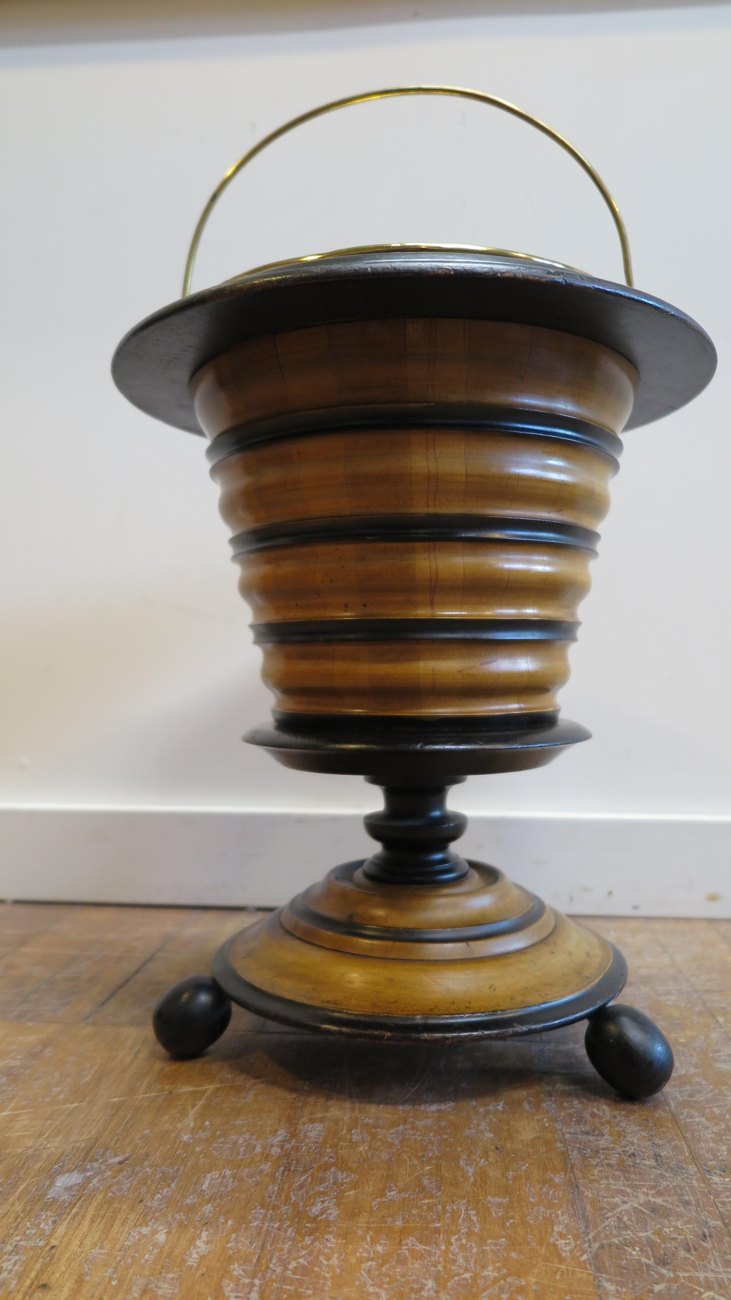 Antique European peat burner. Wonderfully constructed turned wood sections of light and dark having a removable brass bucket with handle. Very decorative in good condition. Some repairs over time are evident. Size is 14 D x 17.5 H with the handle