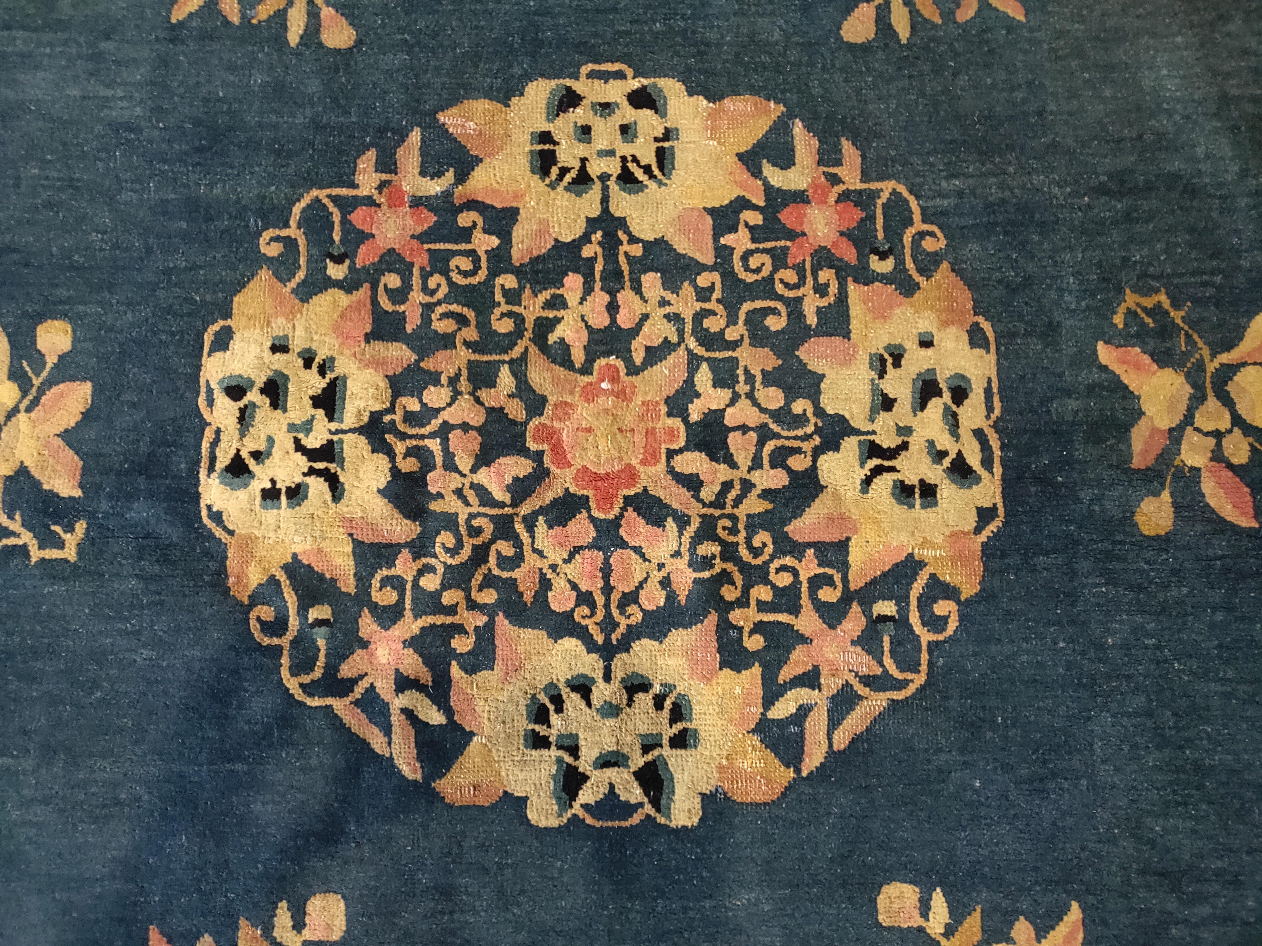 Seasonal flowers are everywhere in this dark blue northeastern Chinese Peking rug, circa 1890. In the circular medallion with its elaborate paeonies; in the floral sprays symmetrically placed in the field, in the beige border with more paeonies,