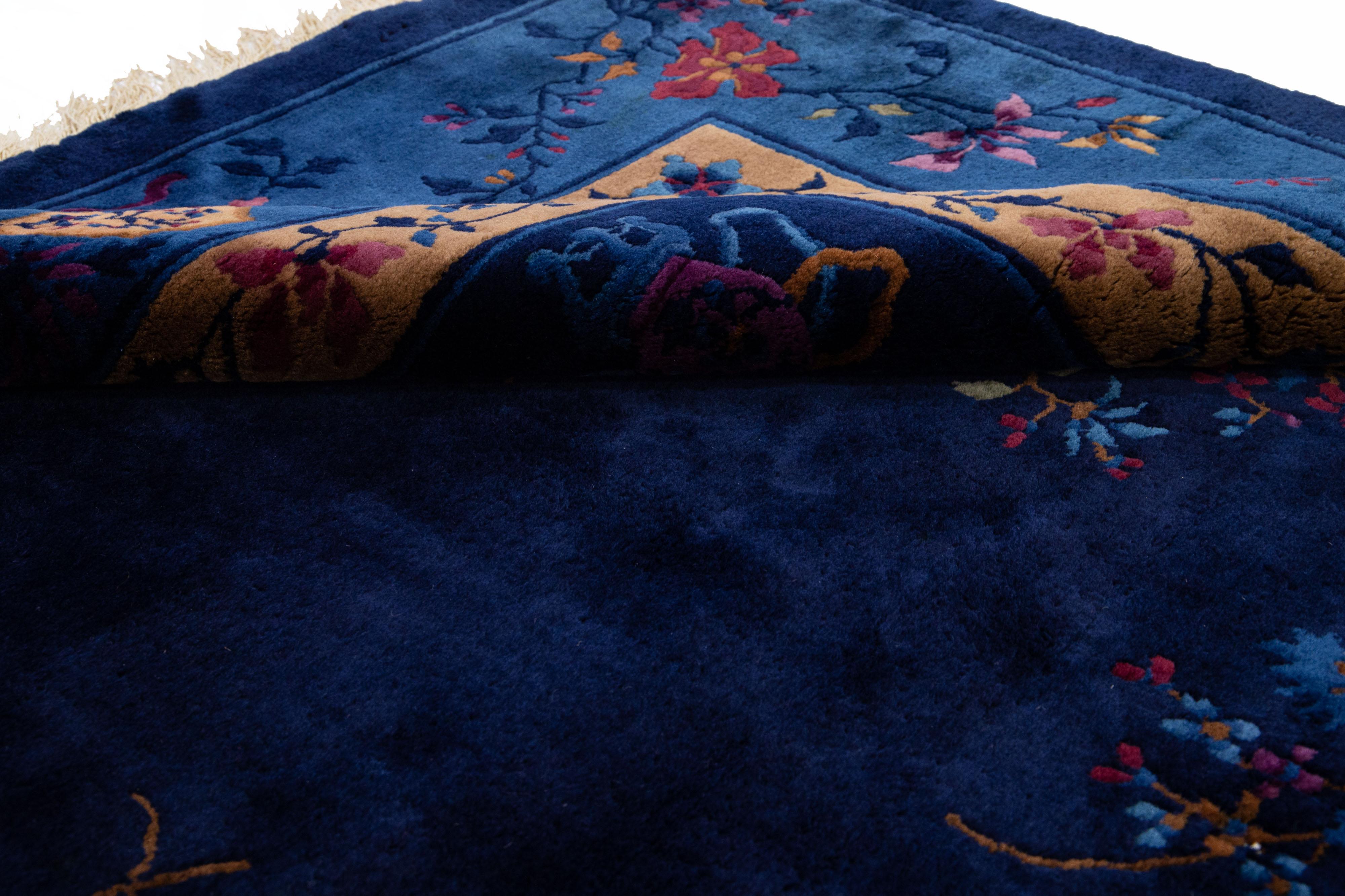 Schöner antiker chinesischer handgeknüpfter Wollteppich aus Peking mit marineblauem Feld. Dieser chinesische Teppich hat einen hellbraunen Rahmen mit mehrfarbigen Akzenten in einem wunderschönen, floralen chinesischen Muster. 

Dieser Teppich