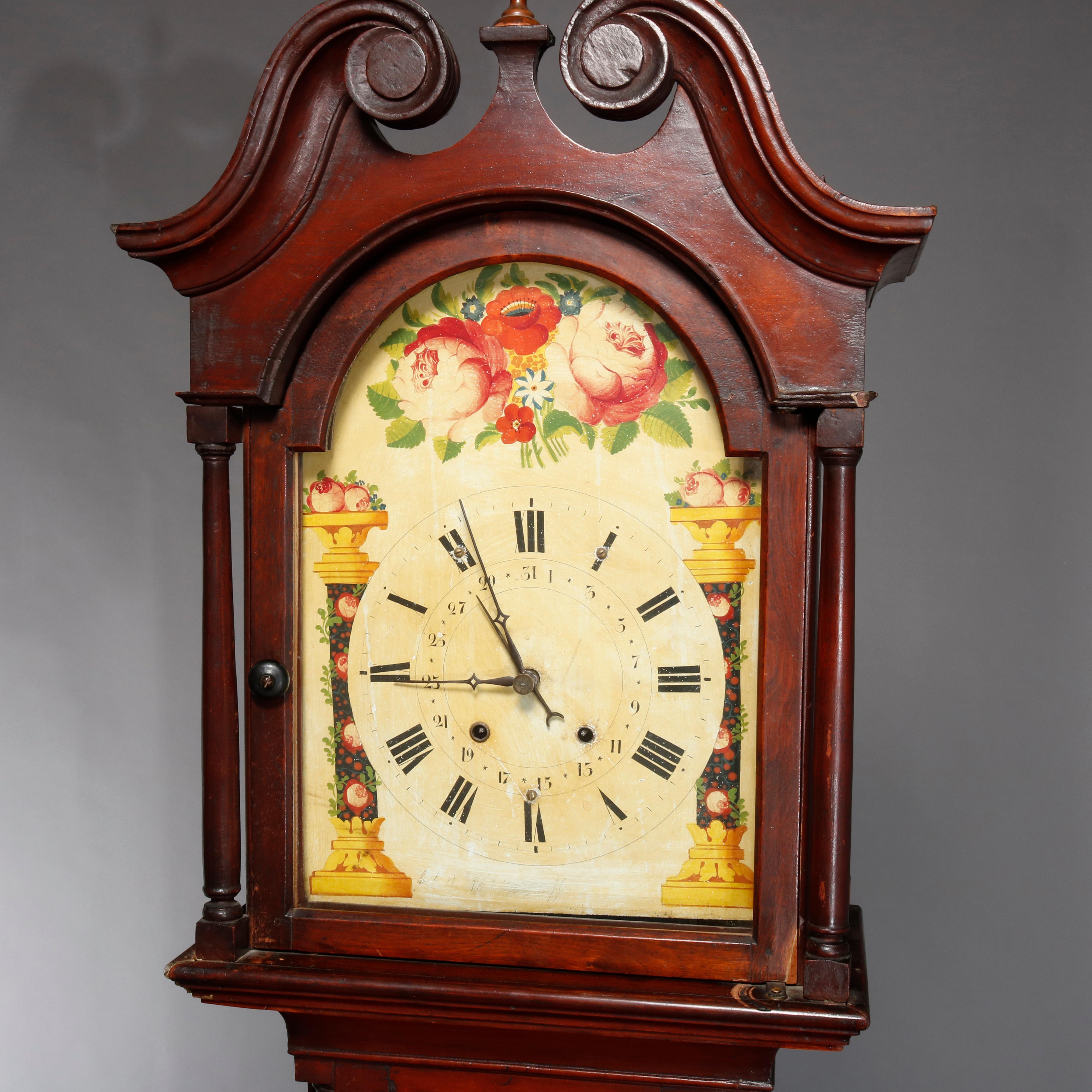 An antique Pennsylvania Federal longcase clock offers mahogany case with broken arch hood with central finial and flanking columns, hand painted floral face with Roman numerals, 18th century.

Measures: 99.25