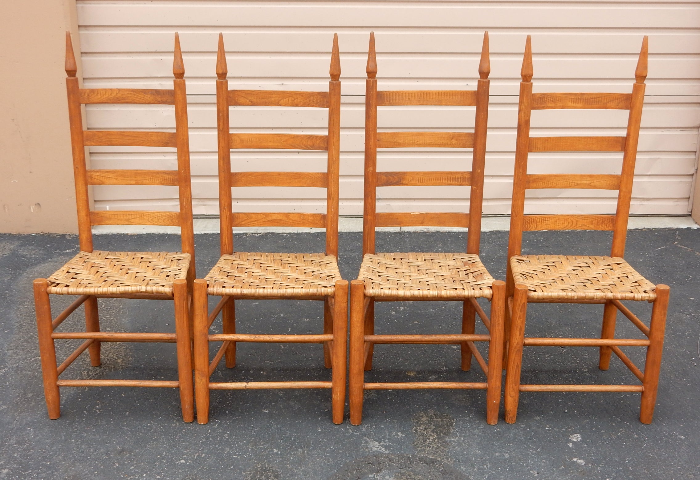 4 Stühle im Stil der Shaker-Ära aus massivem Eichenholz mit Leiterrücken.
Wir glauben, dass es sich dabei um eine Version von Anfang 1900 handelt. 
Die geflochtenen Binsen-Sitzmöbel haben eine schöne, warme, gealterte Patina, aber keine