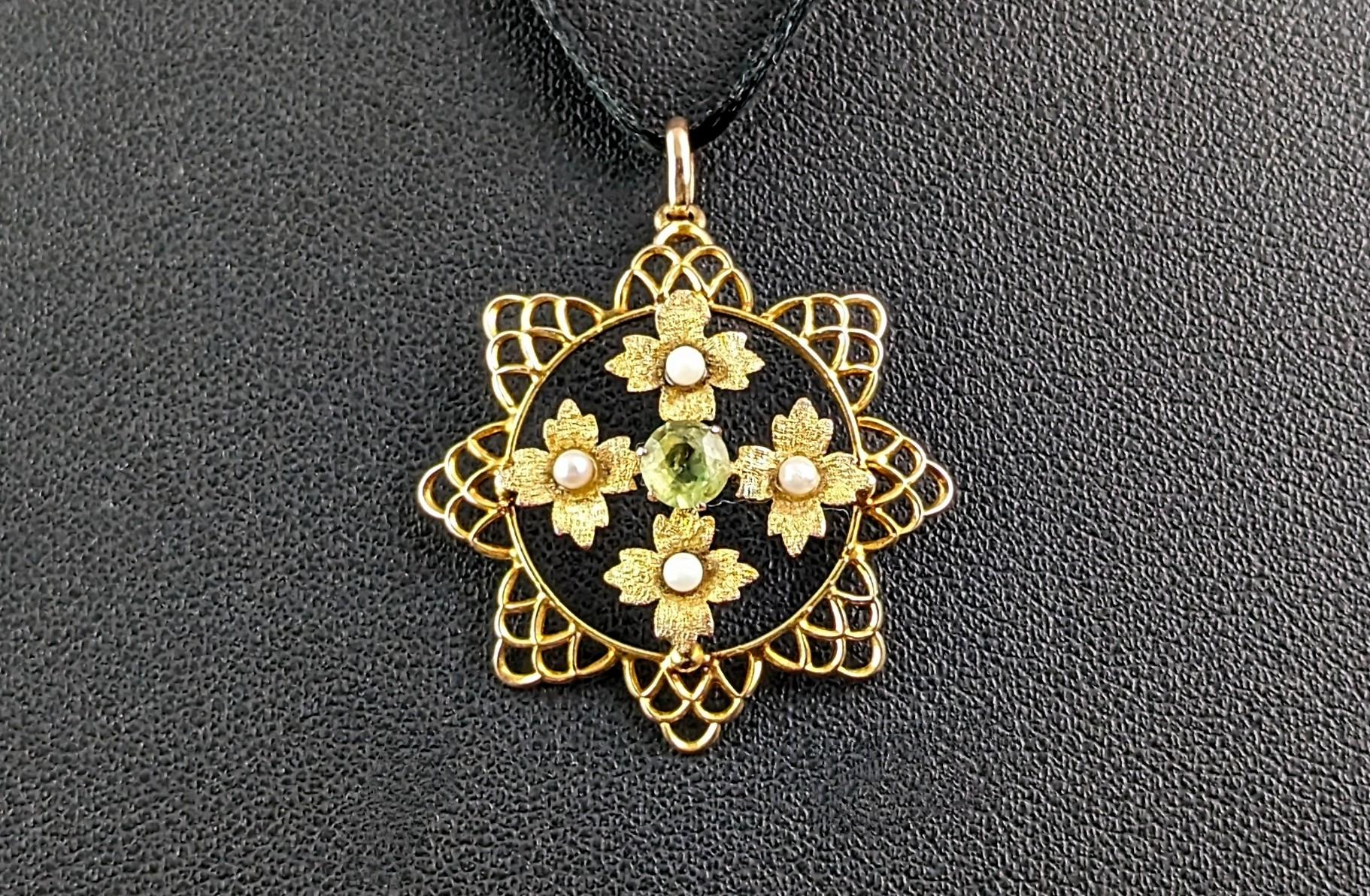This beautiful antique peridot and pearl floral pendant is so pretty and elegant.

It is a flower almost sunflower shaped piece with an openwork design with a quad of textured leaves within each set with a single creamy seed pearl.

To the centre