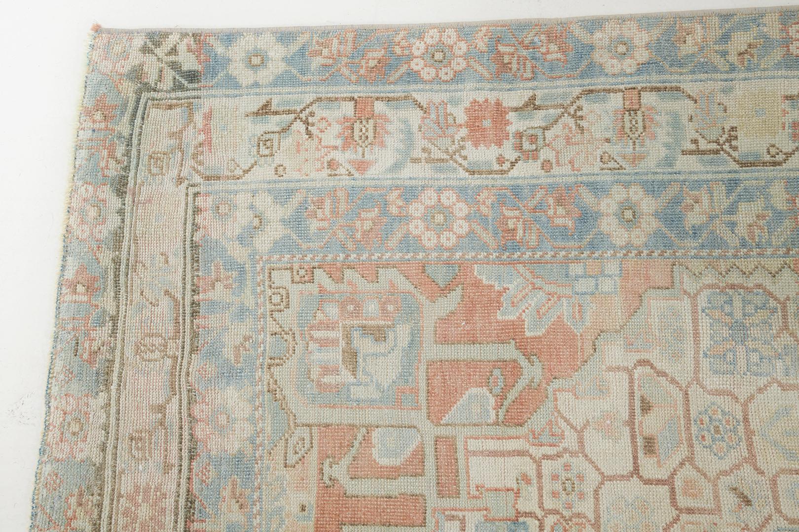 A beguiling antique Persian Afshar rug that features a stunning muted colour palette of ocean blue and rust. Elegantly composed and highlighting a captivating all-over botanical design, this sophisticated rug features a kaleidoscopic effect. This