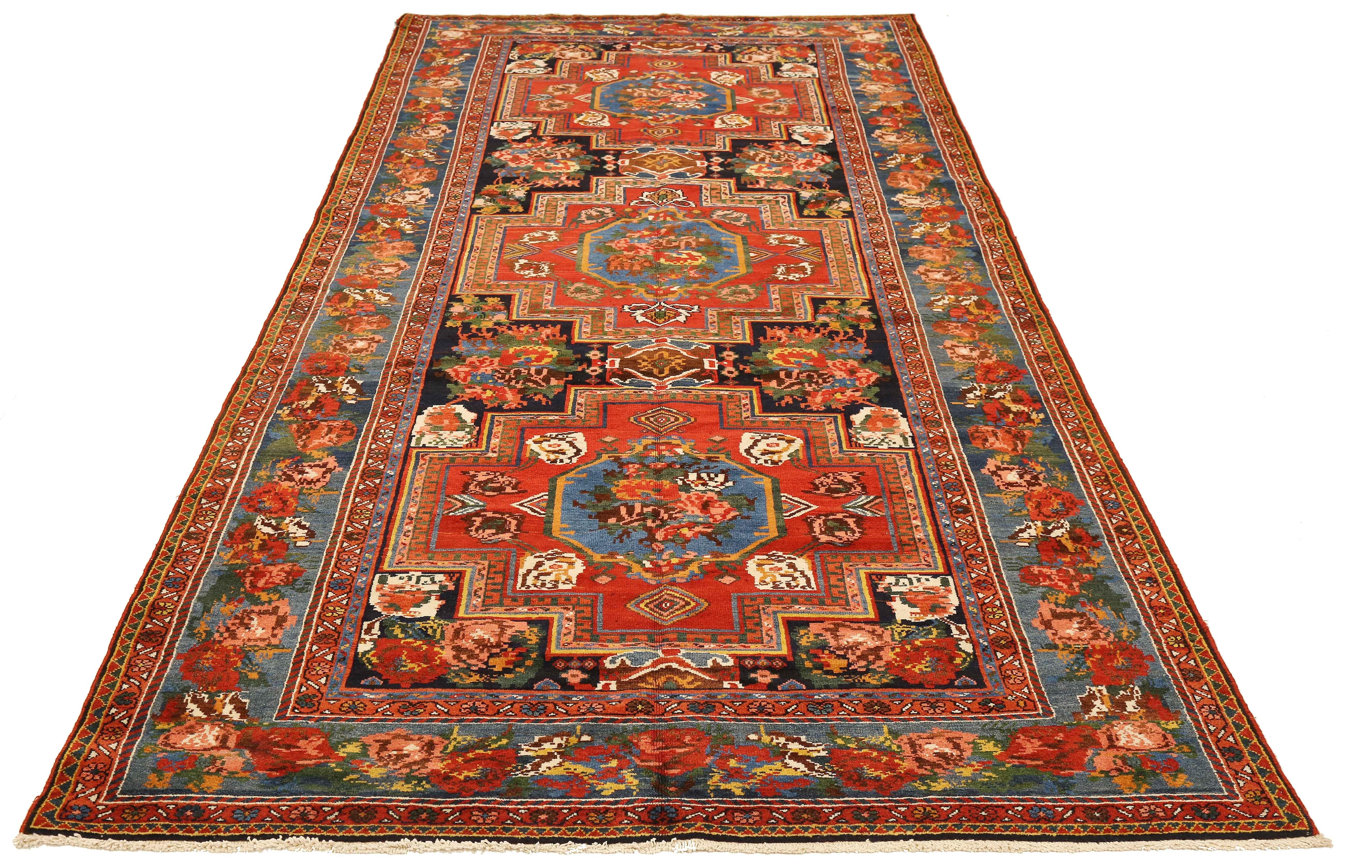 Antique Persian runner rug handwoven from the finest sheep’s wool and colored with all-natural vegetable dyes that are safe for humans and pets. It’s a traditional Bakhtiar design highlighted by blue and red floral medallions over a navy and ivory