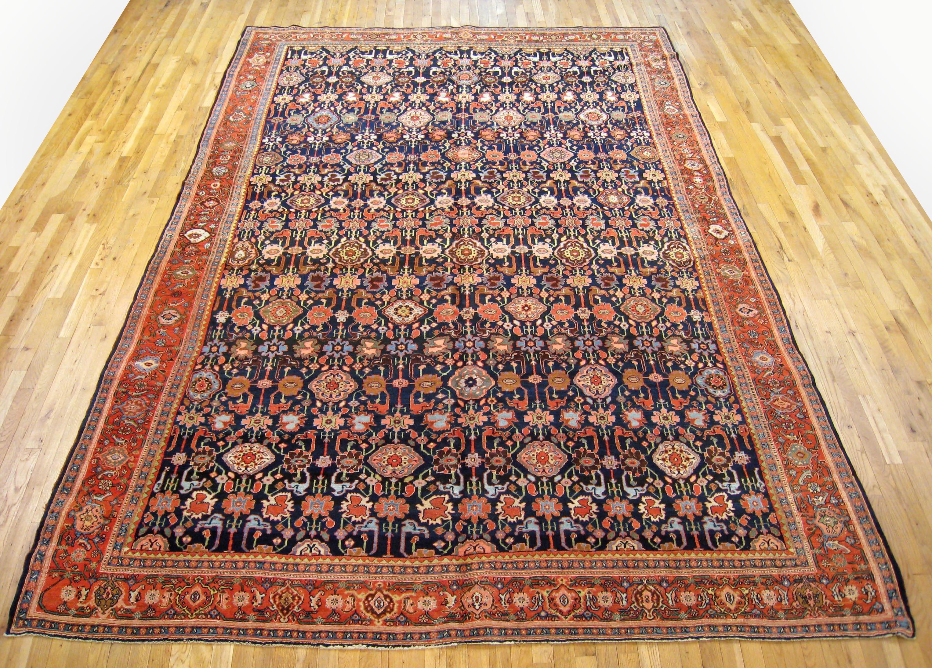 Antique Persian Bidjar rug, Room size, circa 1910

A one-of-a-kind antique Persian Bidjar Oriental Carpet, hand-knotted with soft wool pile. This beautiful rug features a repeating florettes design, on the navy primary field, with a red outer