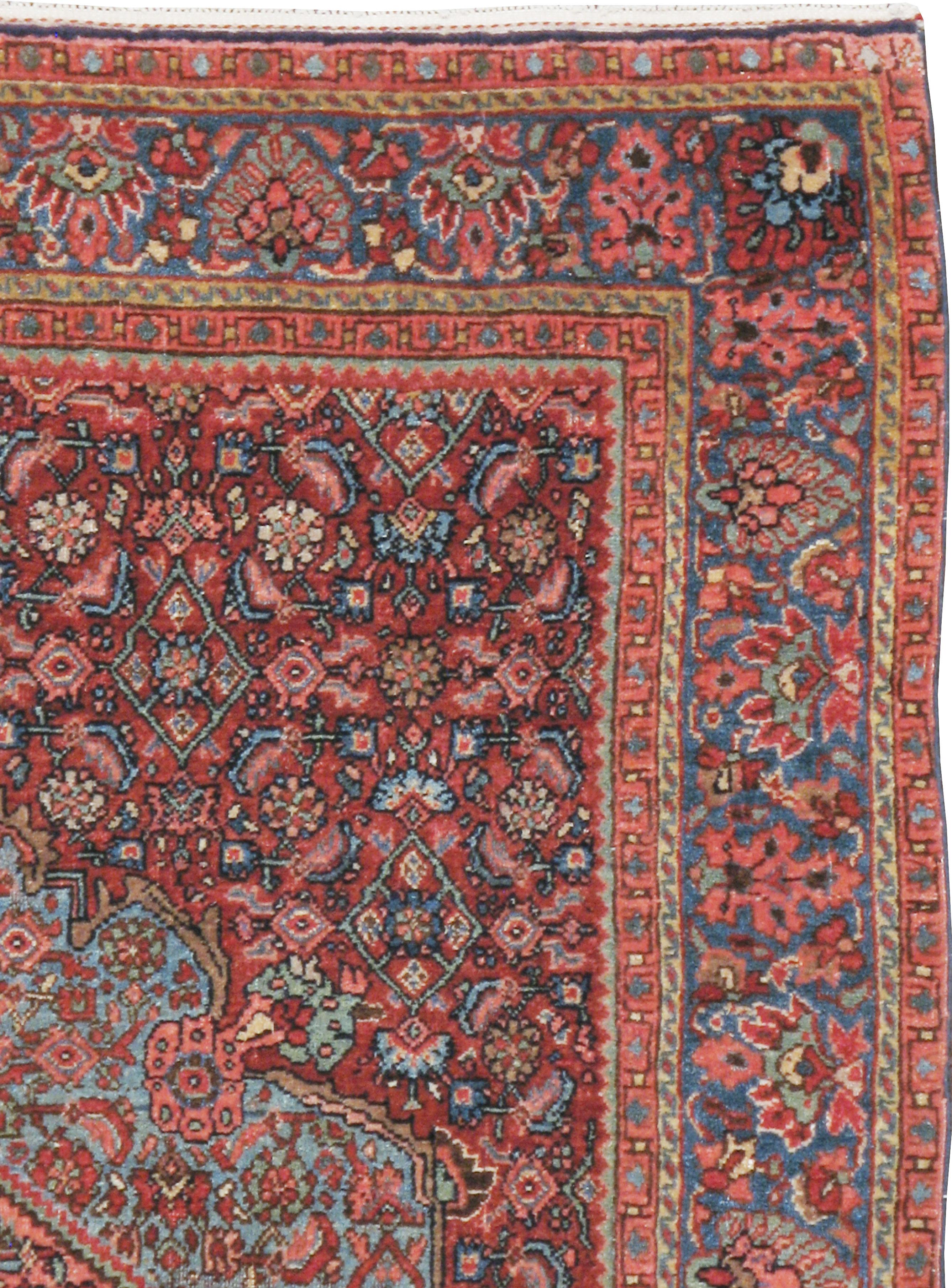 An antique Persian Bidjar rug from the early 20th century. The wine red small Herati pattern field is overlaid by a light blue involute Herati medallion which, in turn, is centered by a hexagonal peach sub-medallion. The medium blue border has