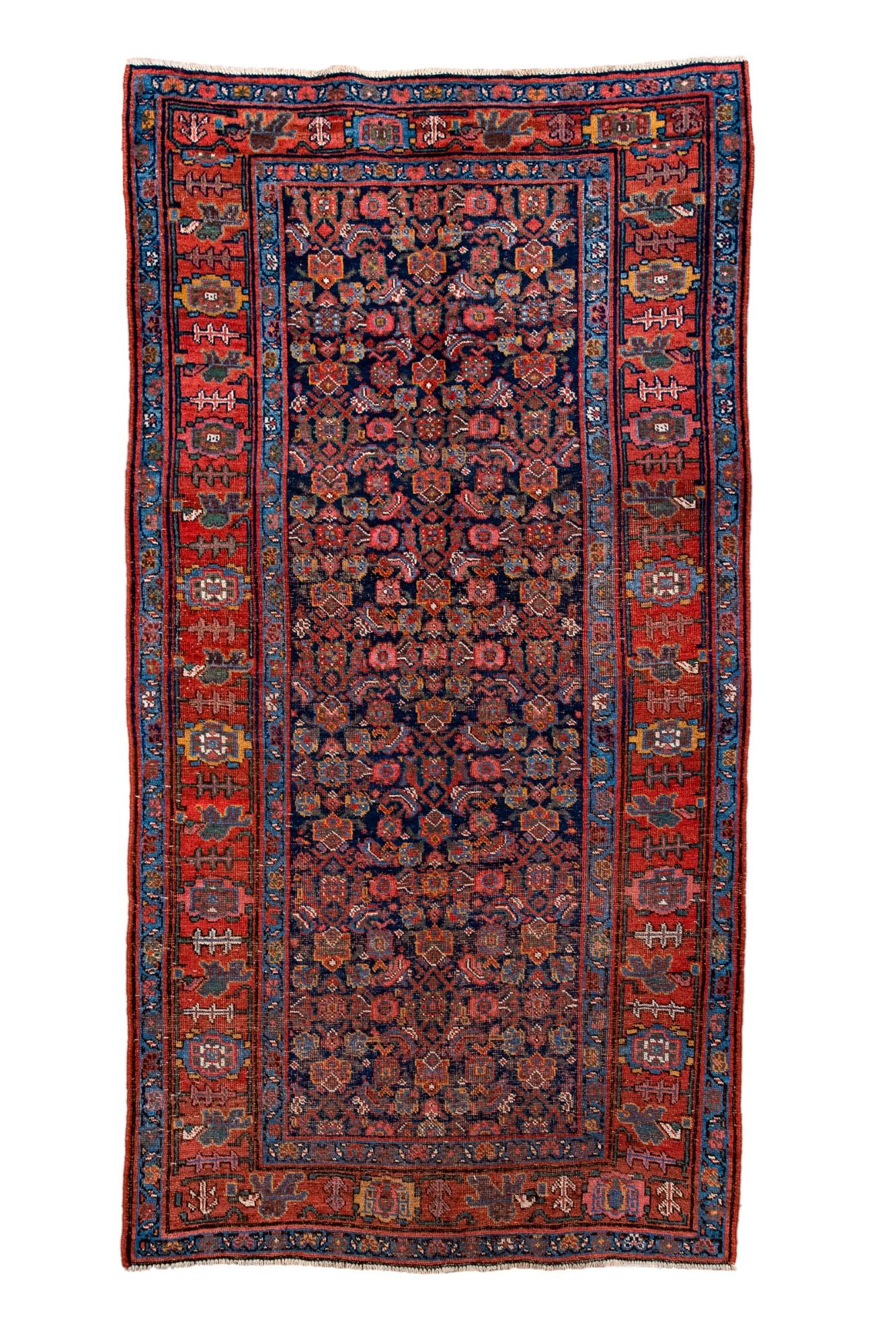 This antique Bidjar rug features a tightly packed allover floral pattern on a deep indigo field, framed by classic red borders filled with stylized rosettes and angular tribal motifs. Known for their durability and weight, Bidjar rugs combine fine
