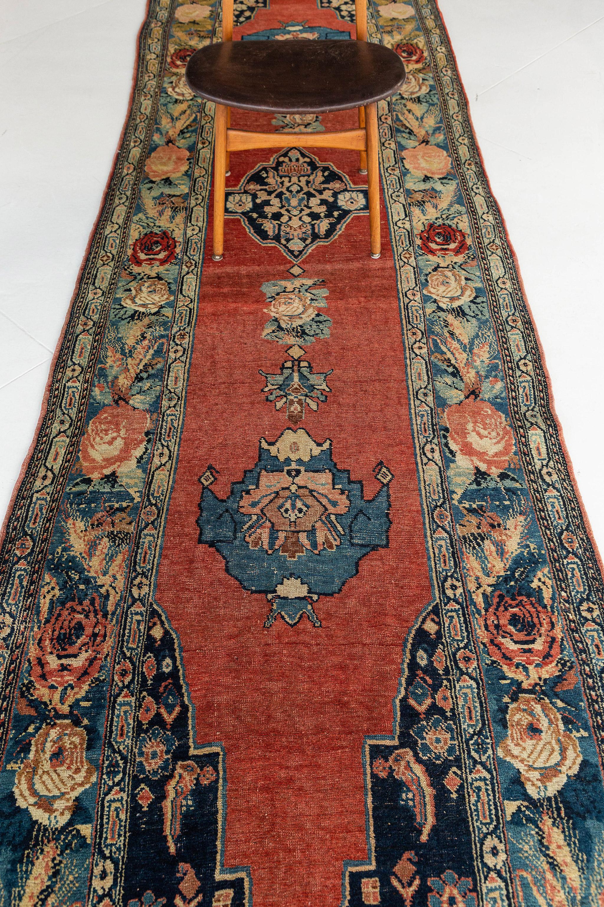 Hailing from Persia or modern-day Iran, this genuine antique Persian Bidjar Runner rug is constructed with beautiful red and blue dyes. Beautifully adorned with three medallions at the center. It is surrounded by gigantic blossoming embellishments