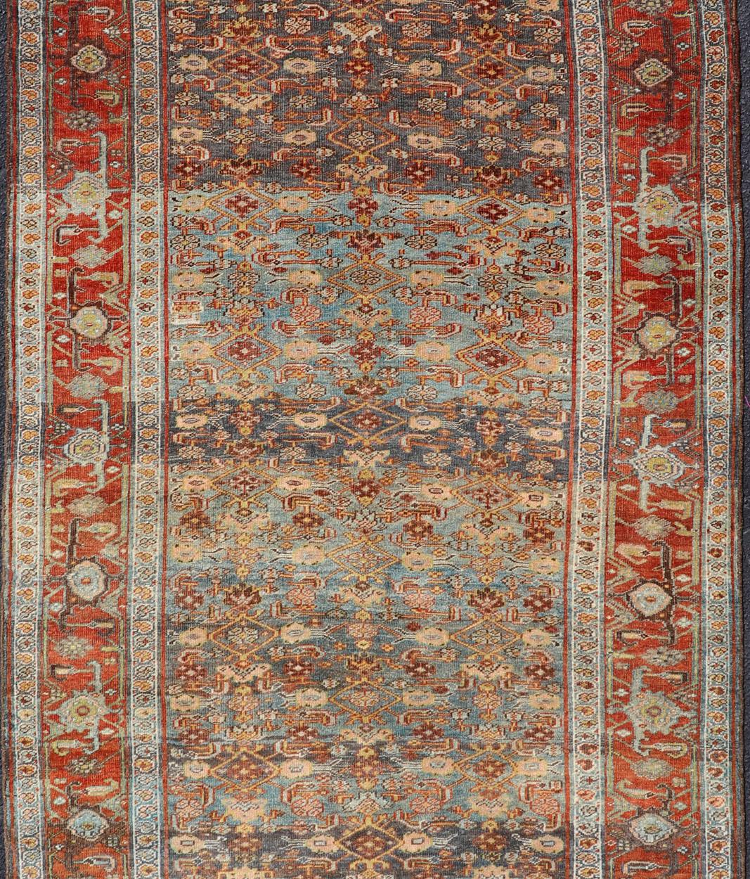 This antique hand-knotted Persian Bidjar short gallery sized rug features a all-over Sub-geometric design throughout the entirety of the piece, and is enclosed within a complementary multi-tiered border. The rug is rendered in various tones of blue,