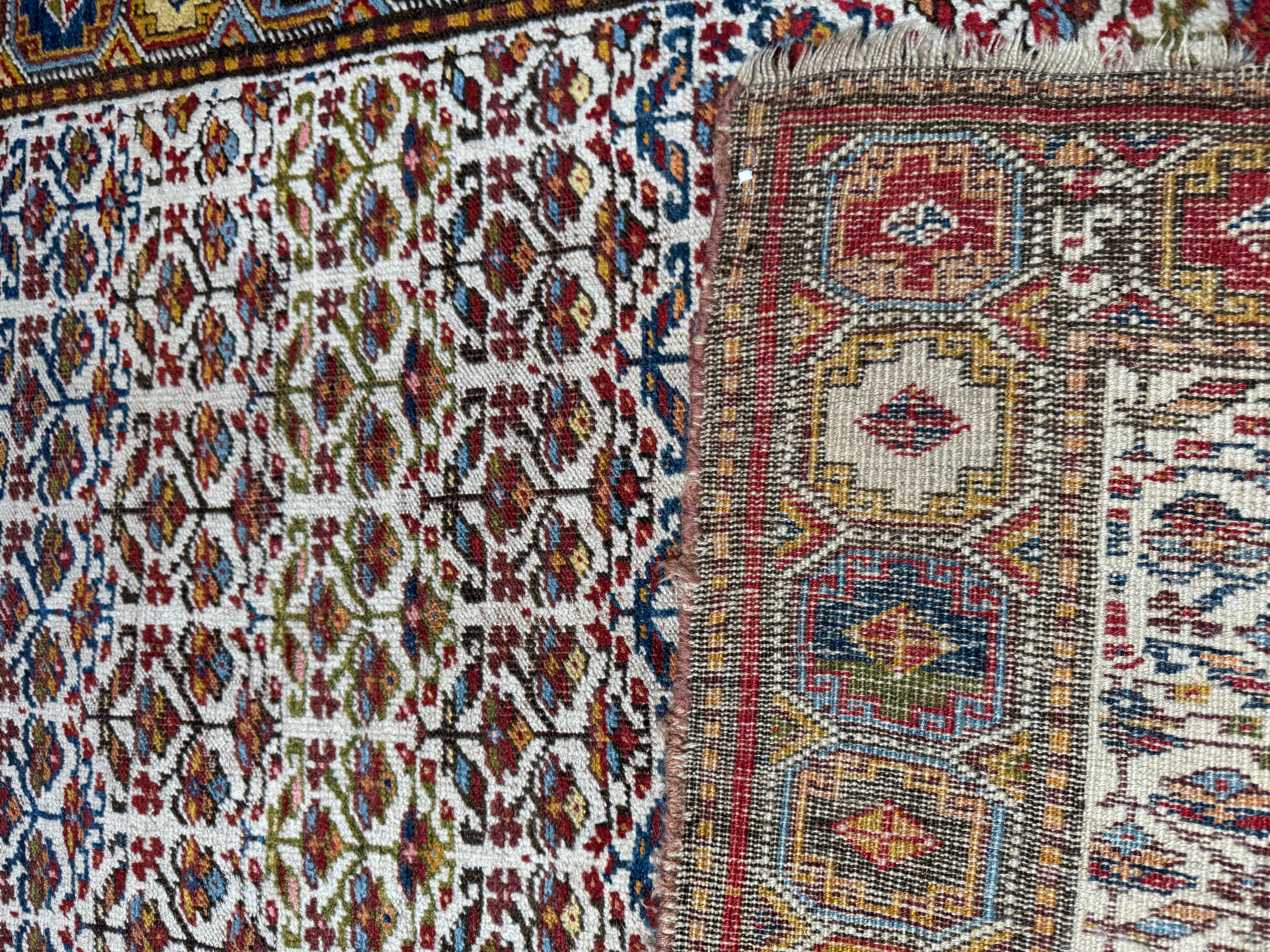 Cet exquis tapis persan vintage Bijar est un chef-d'œuvre de tissage dense et de design audacieux, présentant un motif classique Herati dans de riches tons de joyaux sur un champ ivoire doux. Encadrée d'une bordure géométrique de médaillons