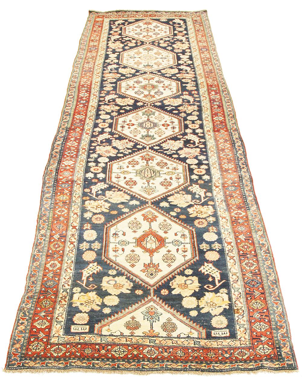Antique Persian runner rug handwoven from the finest sheep’s wool and colored with all-natural vegetable dyes that are safe for humans and pets. It’s a traditional Bijar design featuring colored floral details inside ivory medallions on a navy blue