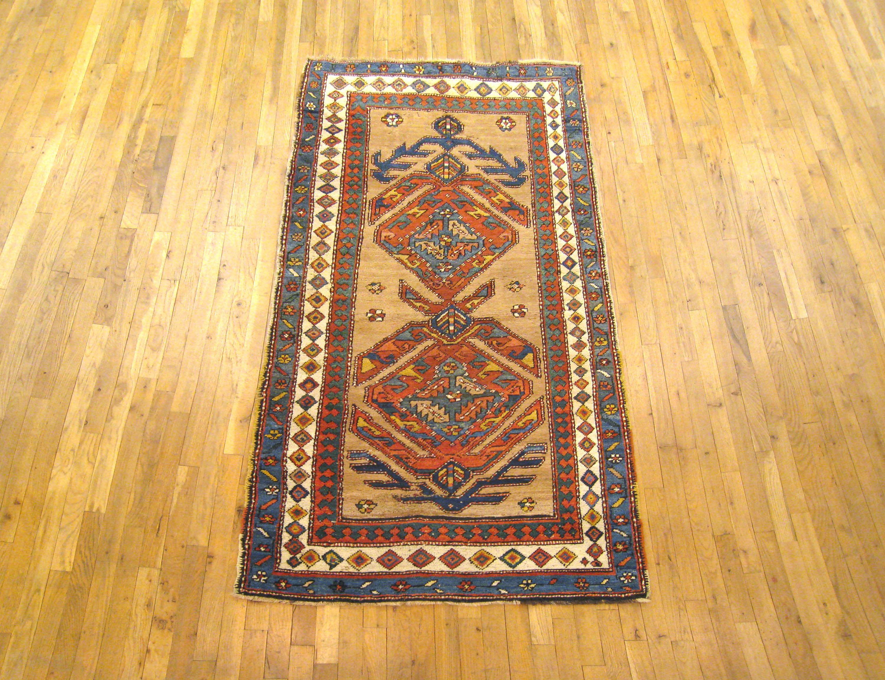 An antique Persian camel hair Serab oriental rug, size 7'4 x 3'6, circa 1900. The rug is characterized by two interconnected geometric medallions on a camel colored field, enclosed within a series of guard borders with diamonds and other geometric