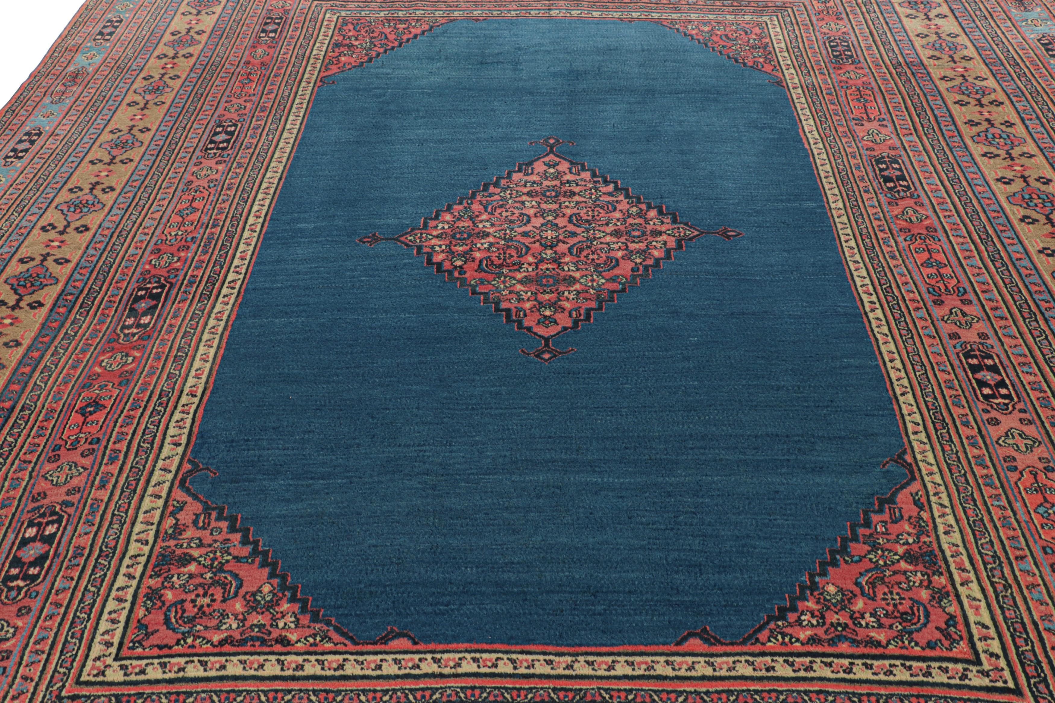 Made with hand-knotted wool and originating from Persia circa 1900-1910, this 10x13 antique Doroksh rug features a minimalist teal-blue field with a central diamond medallion surrounded by multiple ornate geometric borders in coral-red and camel