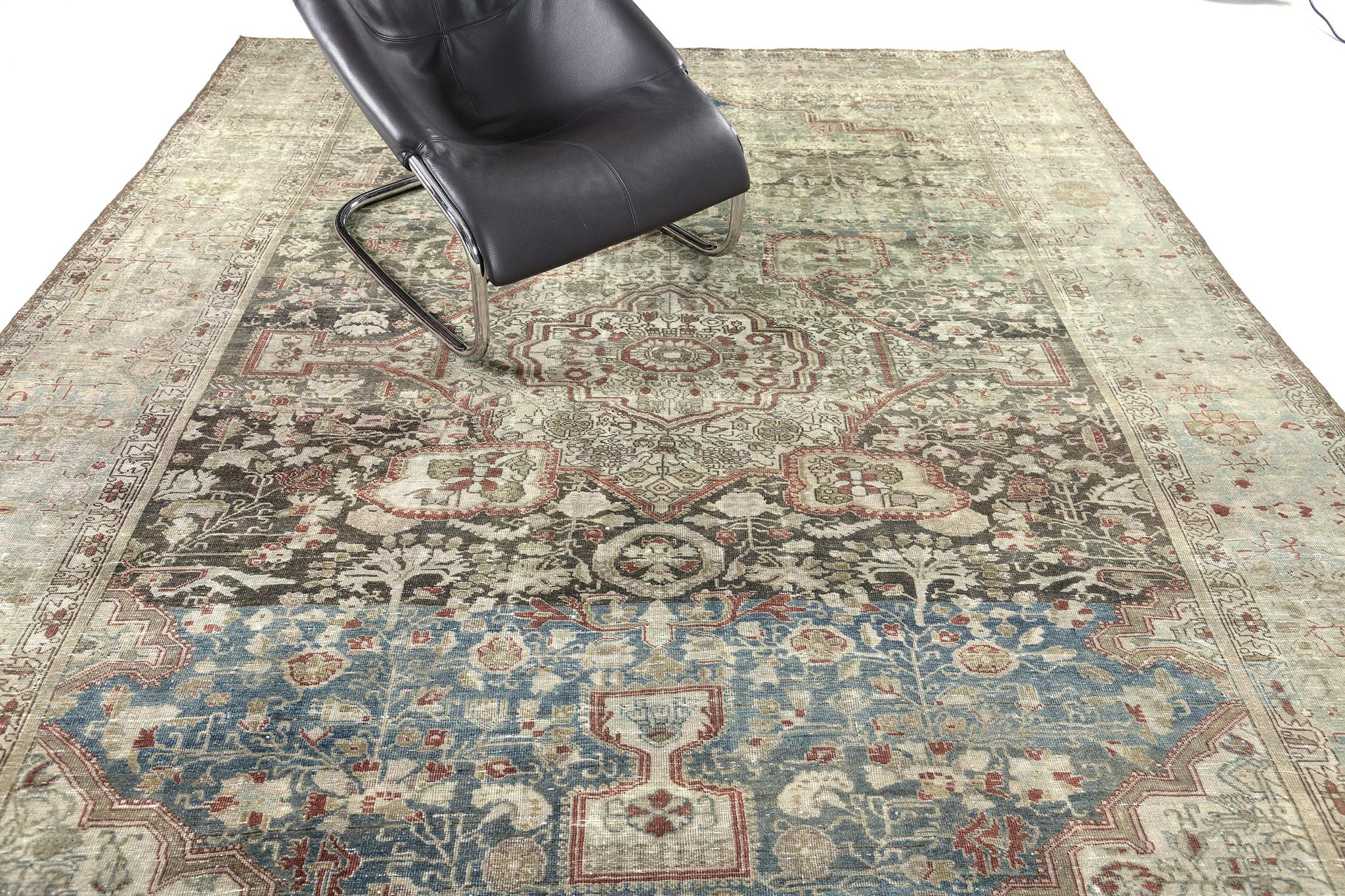 An alluring antique Persian Farahan rug that compels you to an all-over pattern of botanical elements that are woven to impress. The abrashed taupe field is covered by majestic patterns of blooming palmettes, alluring blossoms, and symmetrical