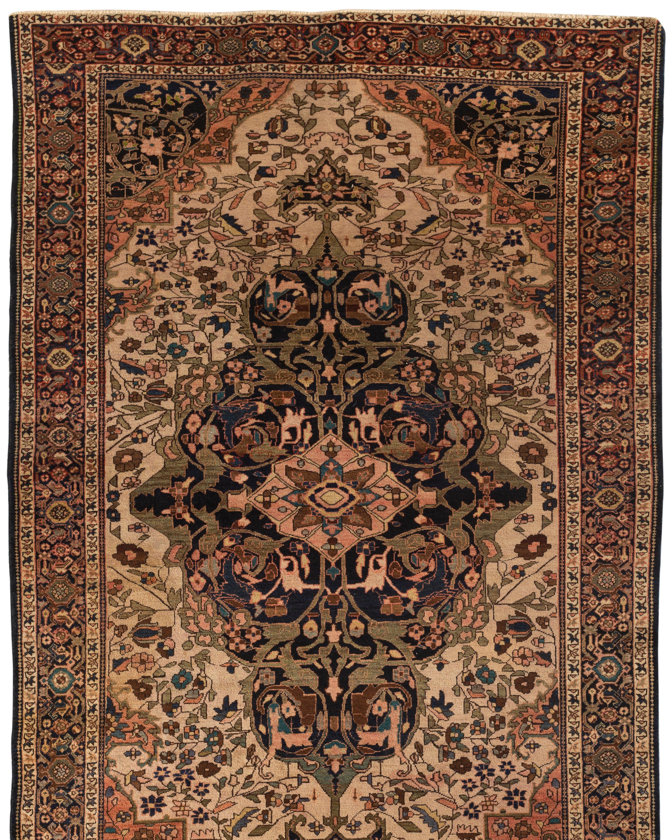 Antique Persian Farahan Sarouk rug, circa 1890. Sarouk rugs come from west central Persia. This attractive small rug has a soft ivory field surrounding a central medallion in navy, blues and soft rose all enclosed within a navy main border creating