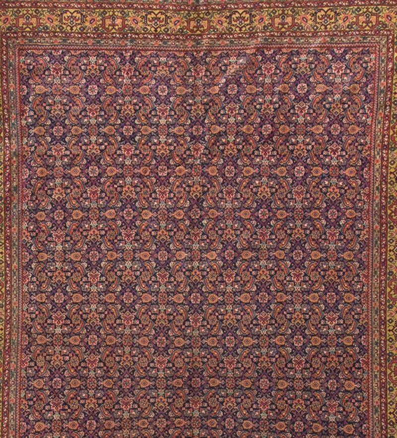 An antique Persian Feraghan that features a dark blue field with multicolored floral designs together with swirling vines. All enclosed in an unusual yellow color border itself surrounded by multiple guard borders. Measures: 8'9 x 12'.
