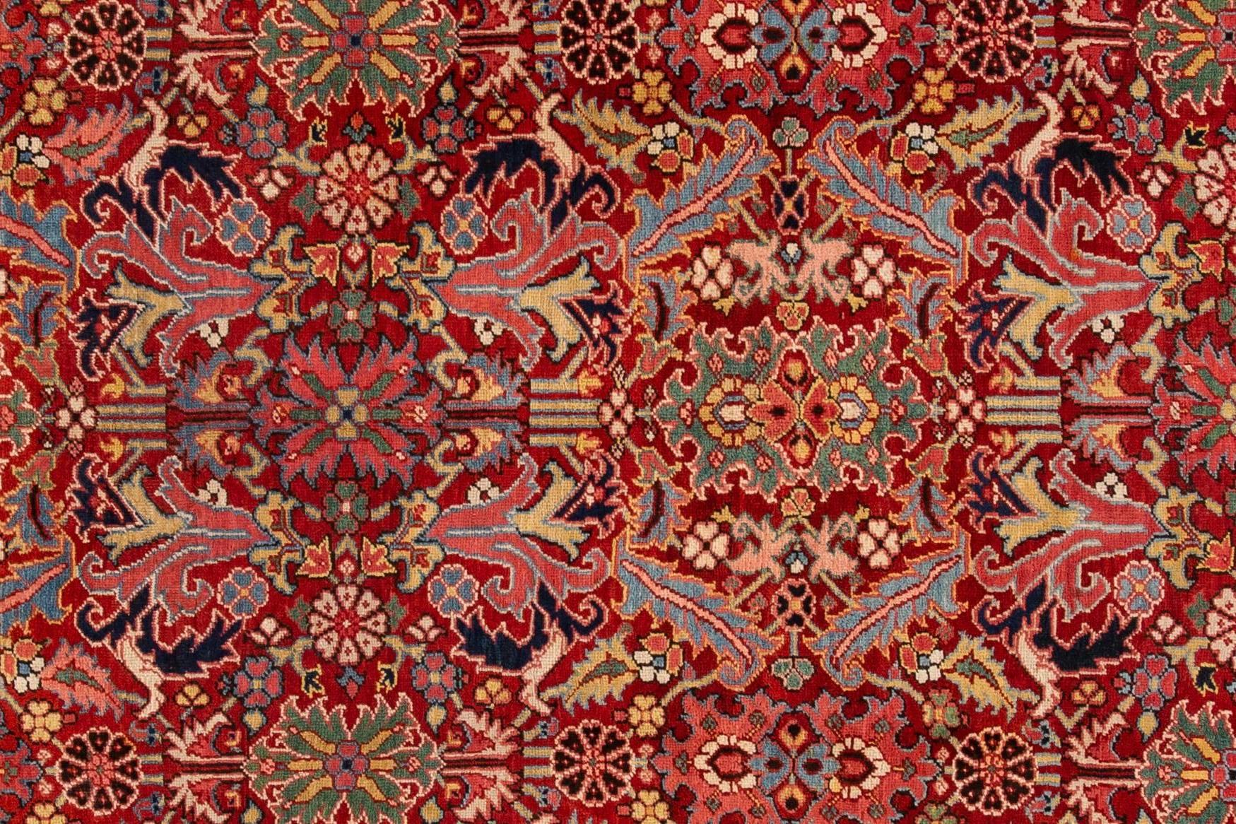 A hand-knotted wool antique Heriz rug with an all-over floral design on a red field. This rug measures 8'4