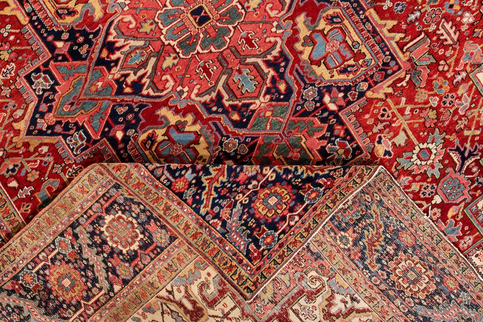A hand-knotted antique Heriz rug with a medallion geometric design on a rust field. This rug measures 9'9