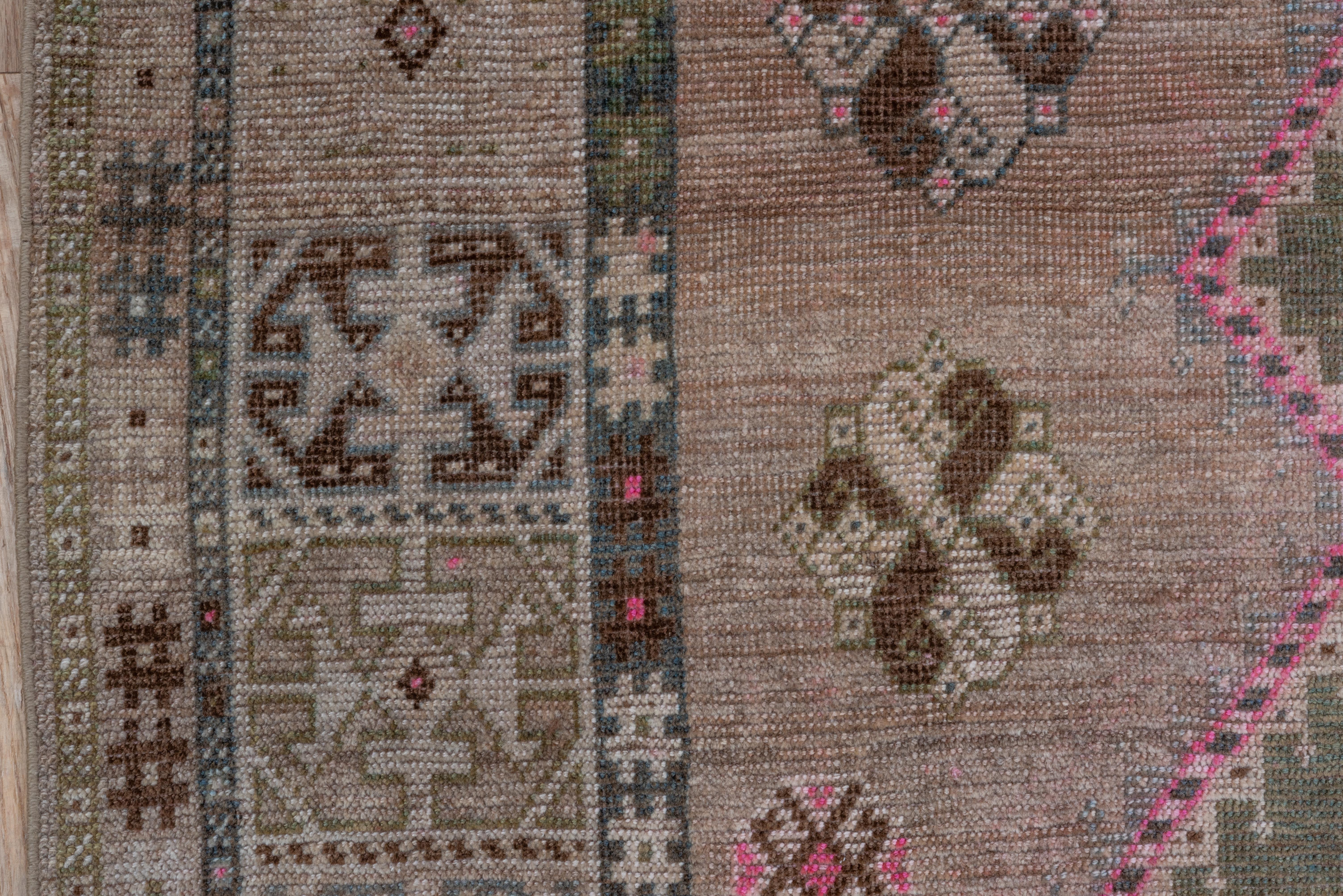 This SW Persian tribal scatter shows a doubly serrated pink triple lozenge pole medallion on a light brown field, with supporting polychrome knot volute rosettes, all within an off white border featuring octogonal 