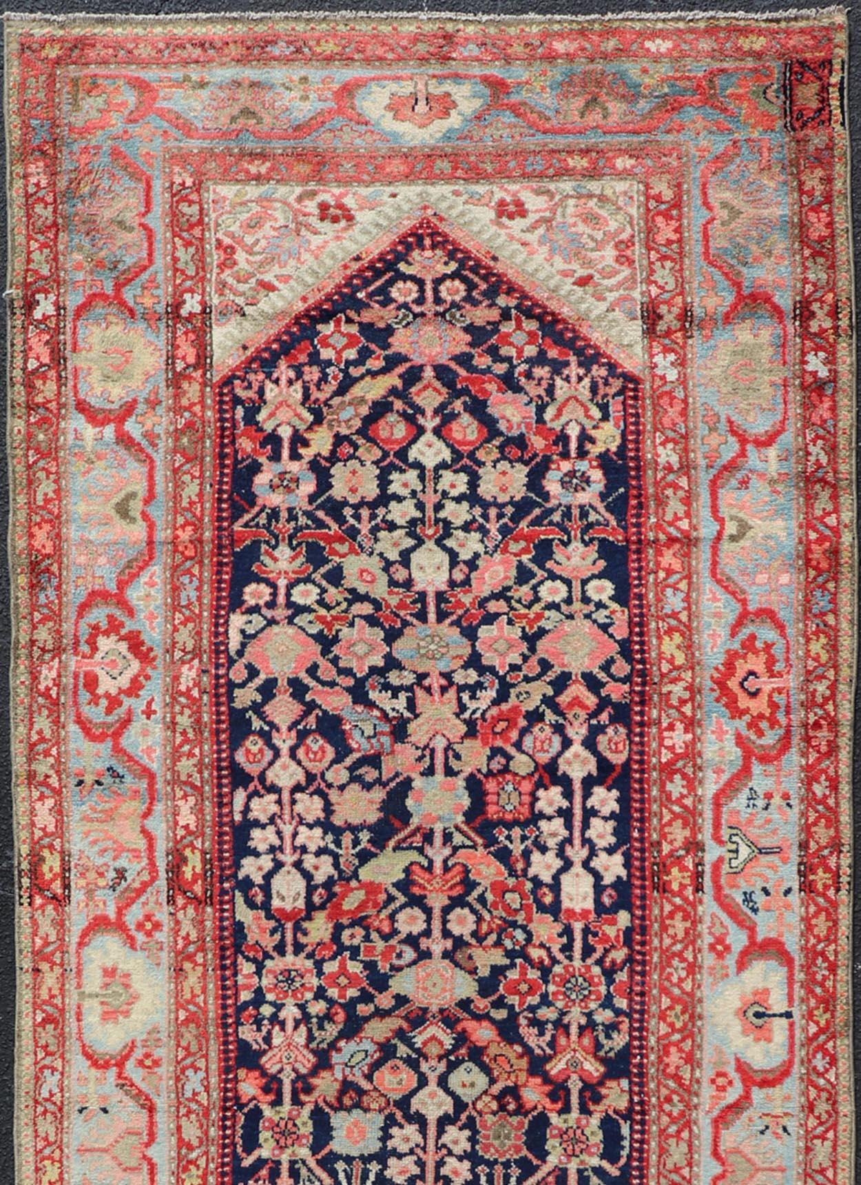 Measures: 4'2 x 11'5 

This antique Persian Hamadan is bright and bold, with a navy background with rich red, pink, sky blue, and pastel accent colors filling the field. The entire rug, from the field cornices to the triple-tiered border is