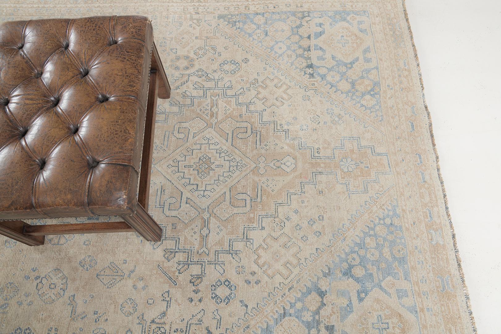 An elegant Antique Persian Ghashghaie rug that showcases a intricate patterns of diamonds laying over the abrashed field of irises and stylized florals that are harmoniously blending together. This enchanting rug features an earthy colour scheme.