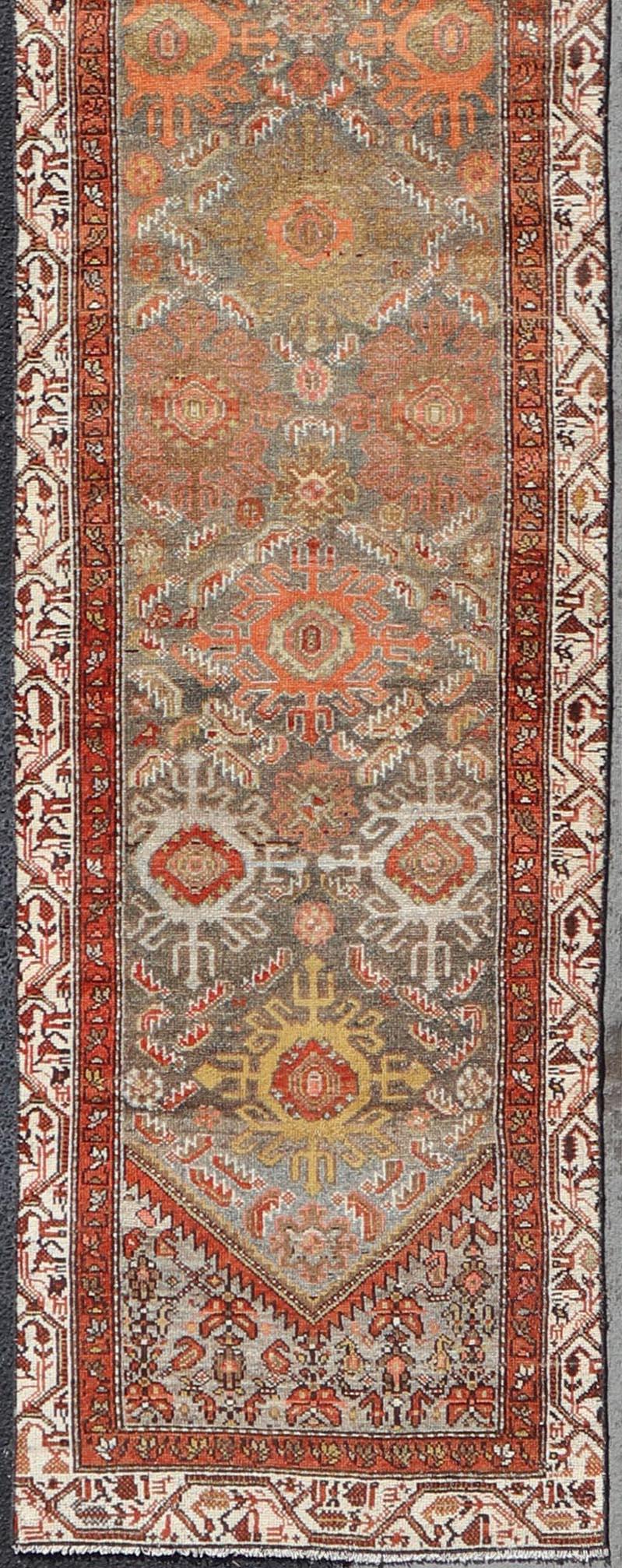 Measures: 2'6 x 16'3 

This runner features a beautiful desert palette of orange, rustic gold, taupe, cream, red, and camel, with a bright ivory border filled with nature motifs. The field holds incredible tribal-like crests proudly displaying the