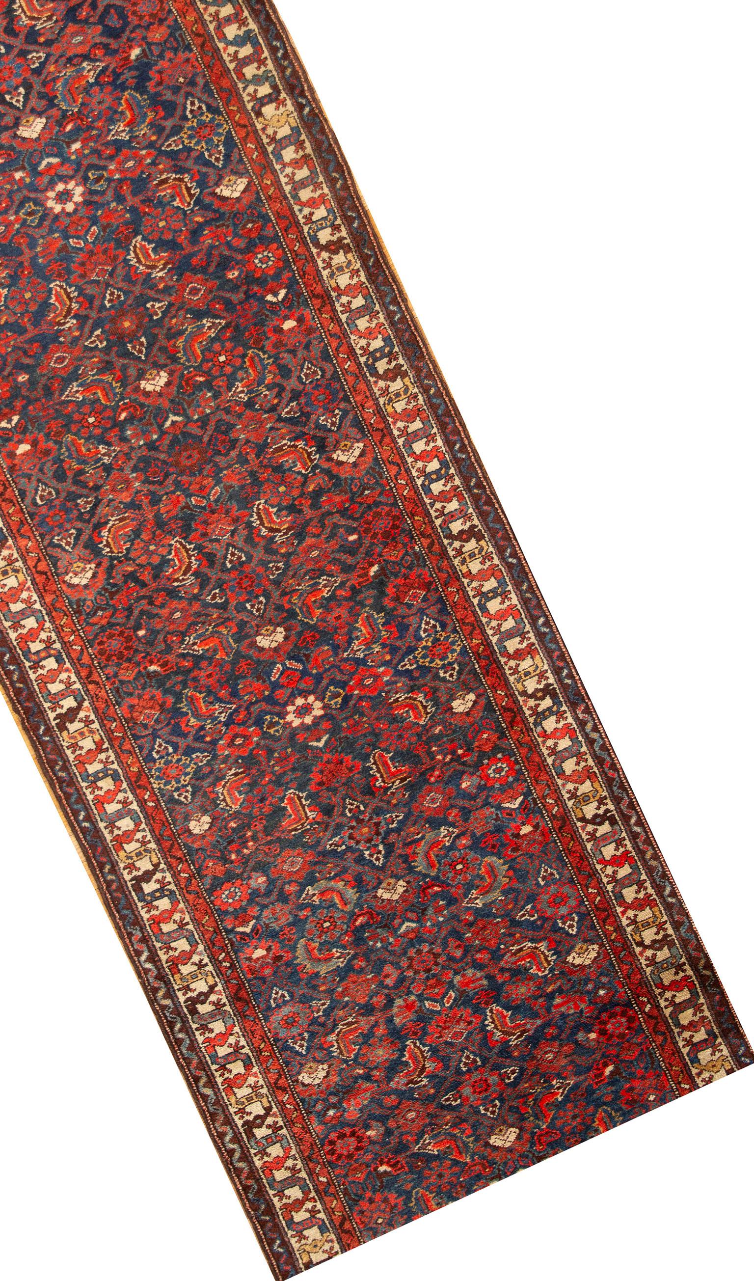 Persian Hamadan runner, circa 1920. Size: 3'4 x 13'4. This lovely, circa 1920s Hamadan Persian runner. Has a profusion of floral motifs on a deep blue ground. Surrounded by an ivory border and two smaller borders this is a joyful runner.