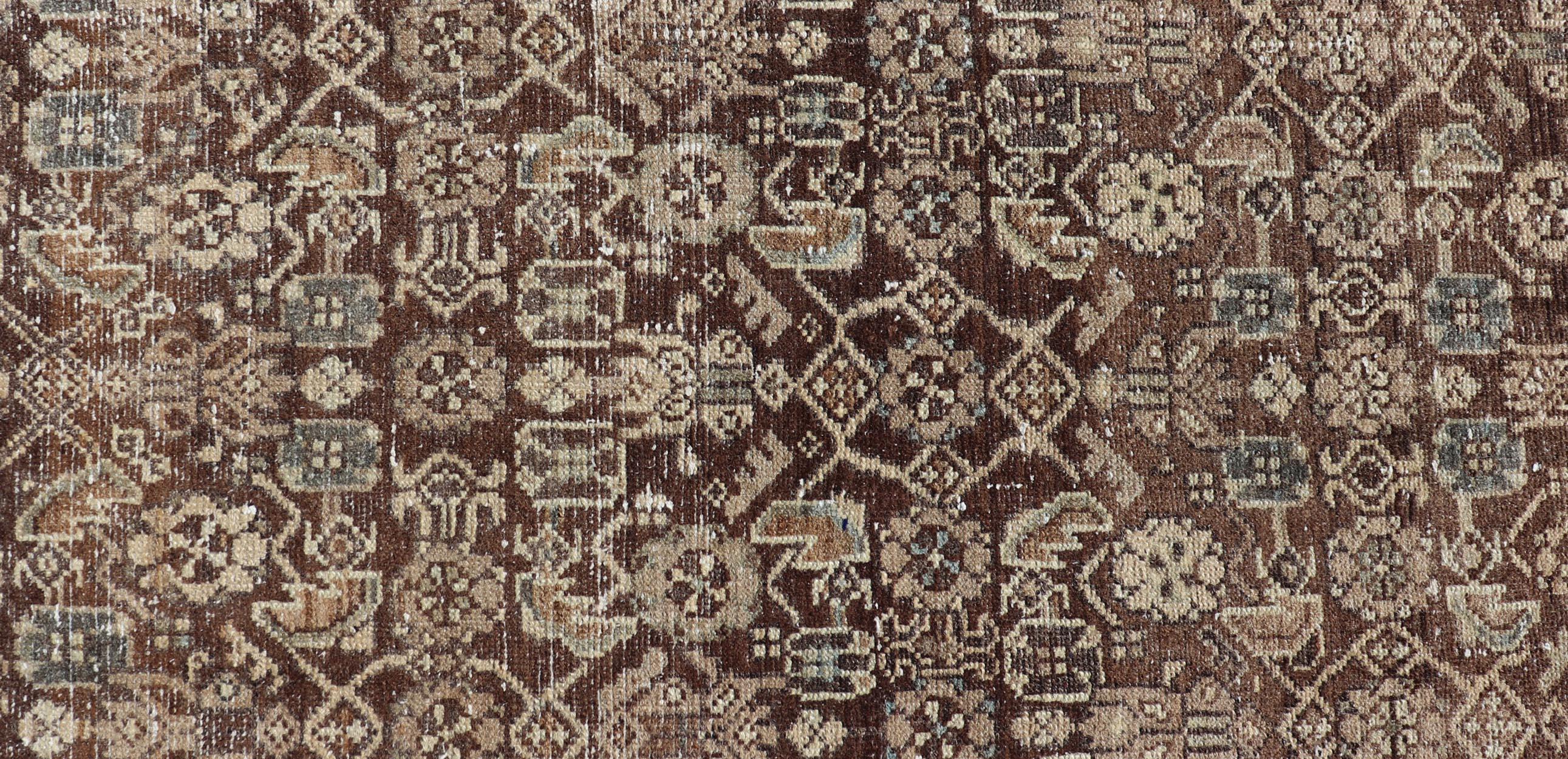 Measures: 2'8 x 13'2 

This antique Persian runner features a palette of brown, cream, camel, and accents light blue. The all-over, sub-geometric floral covers the entire cocoa background. The cream border has a stylized floral patter and a