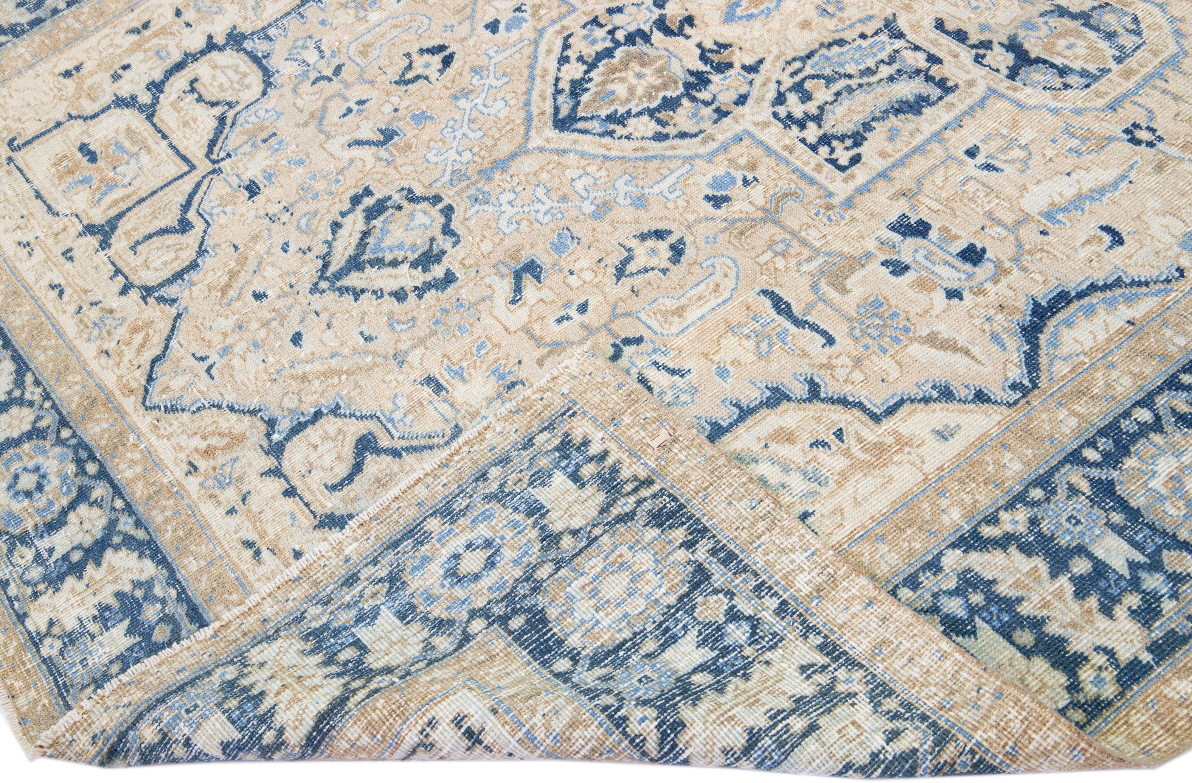 Beautiful antique Heriz hand-knotted wool rug with a beige color field. This Persian rug has a blue frame with tan accents in a gorgeous all-over geometric floral medallion design.

This rug measures: 7' x 9'3