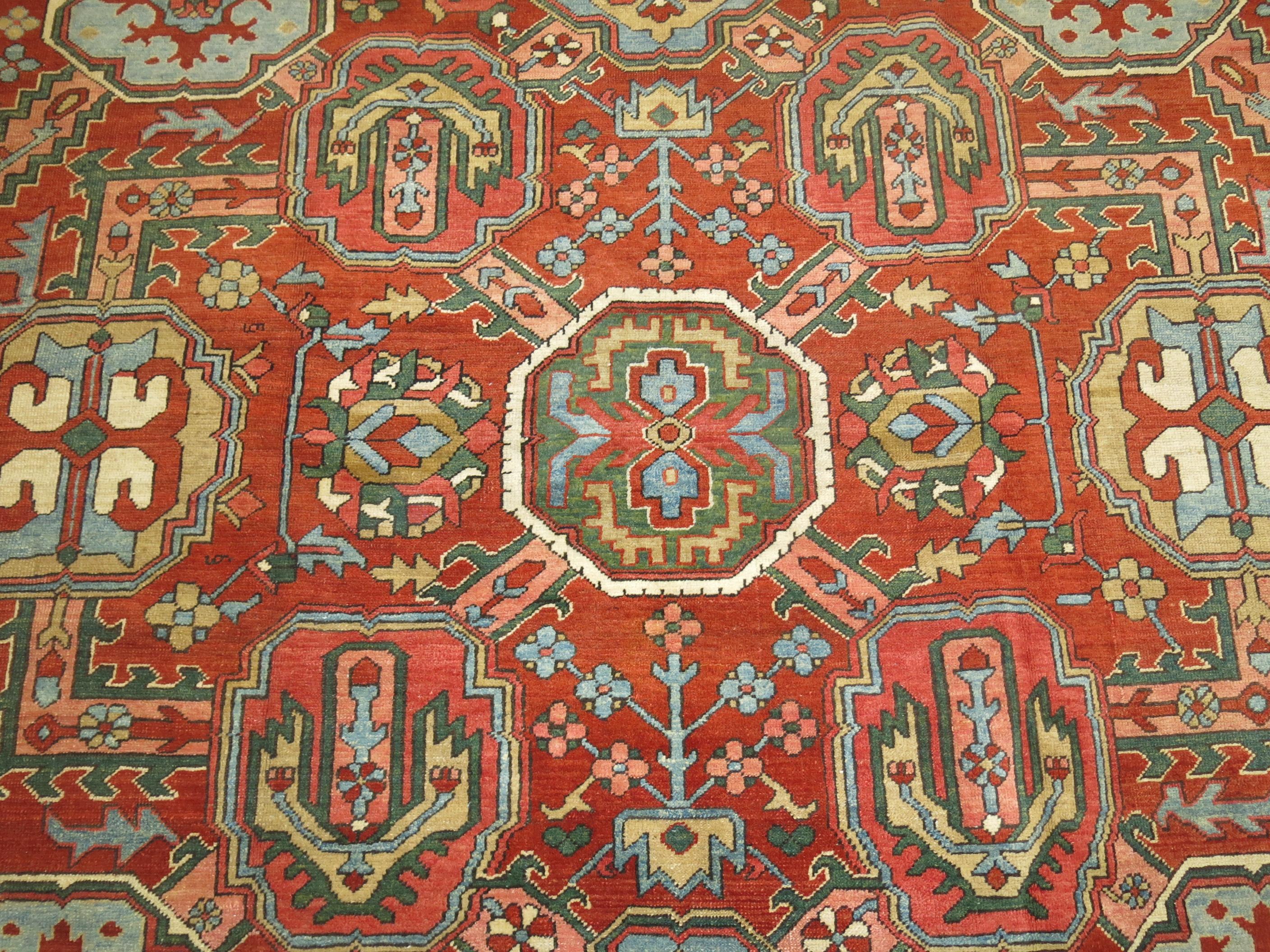 A room size Persian antique Persian Heriz rug. Brick red field, navy border. Dominant accents in olive green, light green, light blue, mustard, pink. Compelling all-over design.
Condition is excellent too. Even Pile throughout,

circa 1920,