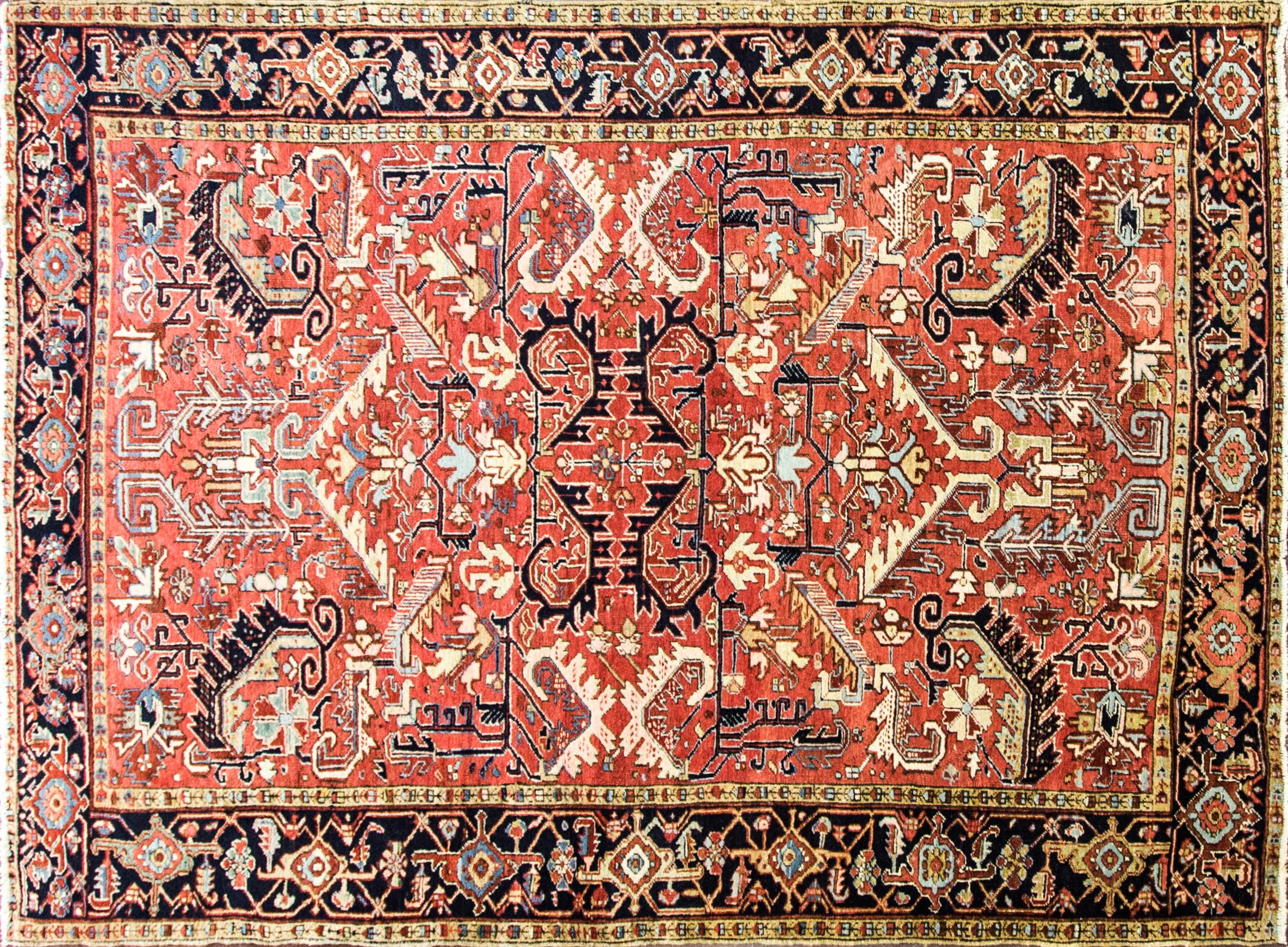 This remarkable and artistic antique rug showcases an ornate, multicolored central design. At the heart of the antique Persian Heriz Serapi rug, a many-petaled flower is surrounded by a 12-pointed stellar shape in light and dark blue. Angular