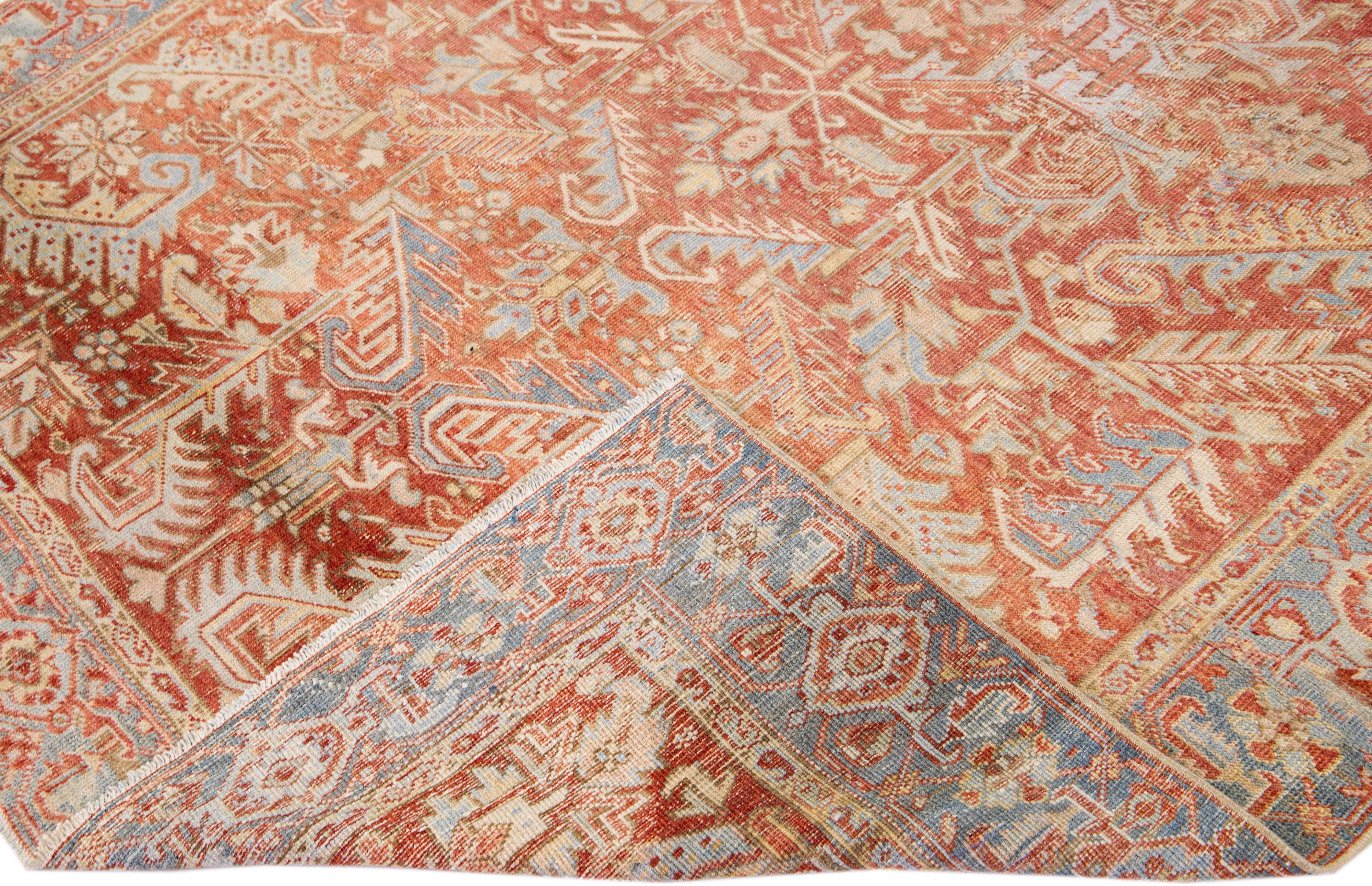 Beautiful antique Heriz hand-knotted wool rug with a rust color field. This Persian rug has a blue frame with beige accents in a gorgeous all-over floral design.

This rug measures: 6'7