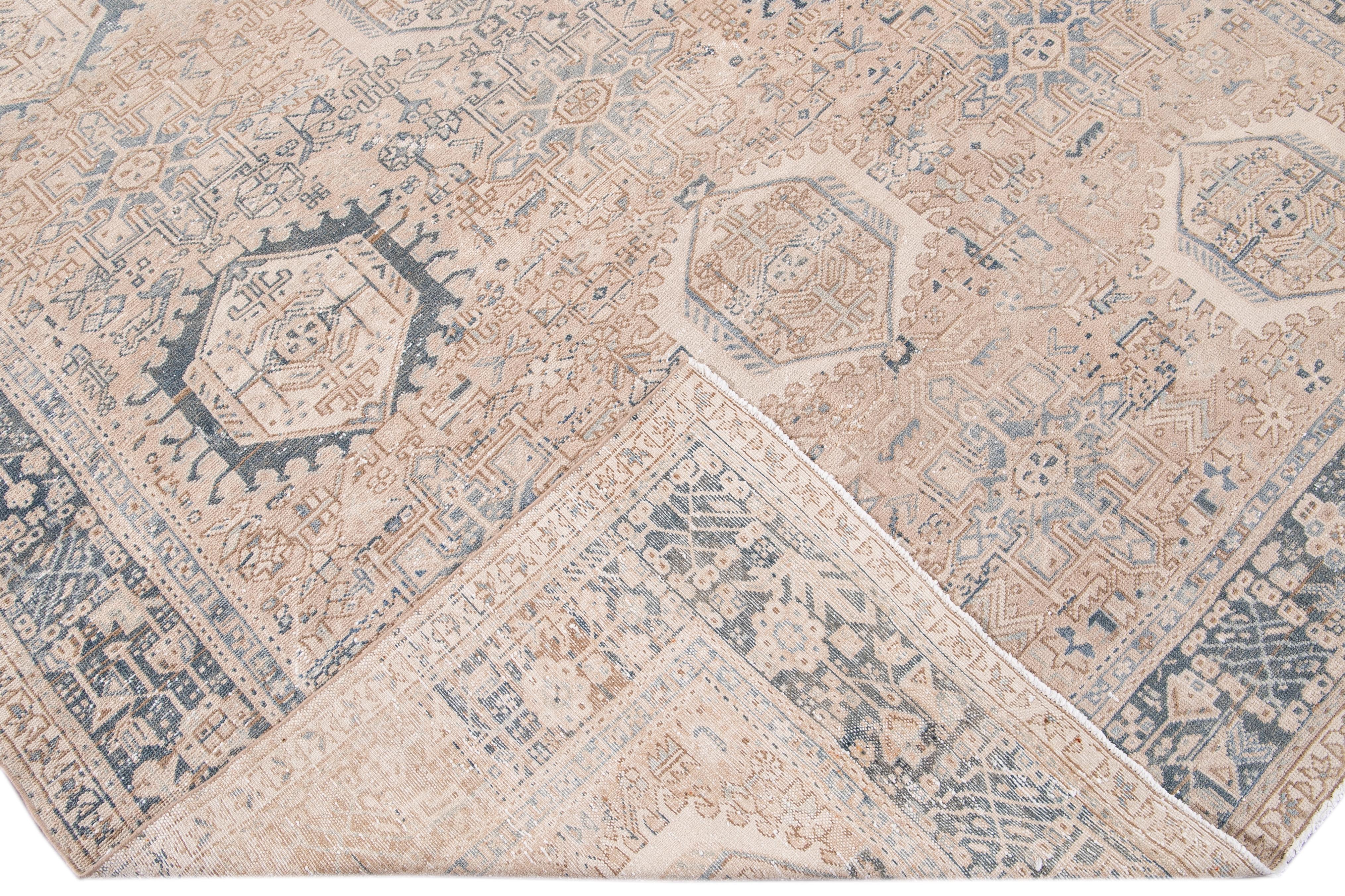 Beautiful antique Persian Heriz hand knotted wool rug with a beige field. This Heriz rug has a blue frame and brown accents in an all-over gorgeous geometric multi-medallion floral design.

This rug measures: 7'10