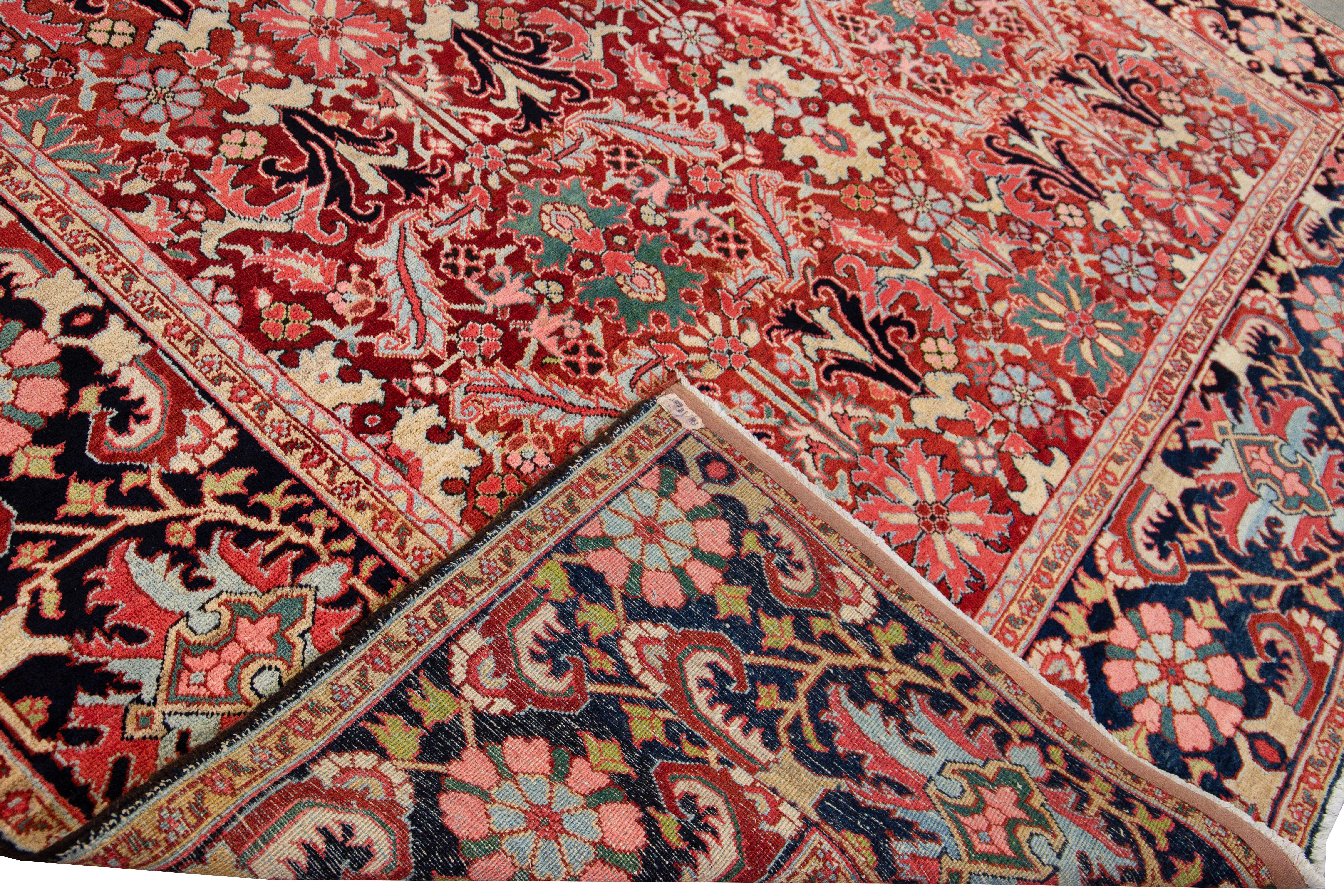 Schöner antiker persischer Heriz-Handknüpfteppich aus Wolle mit rotem Feld. Dieser Serapi-Teppich hat einen marineblauen Rahmen und mehrfarbige Akzente in einem prächtigen floralen Tribal-Muster, das überall zu sehen ist.

Dieser Teppich misst: