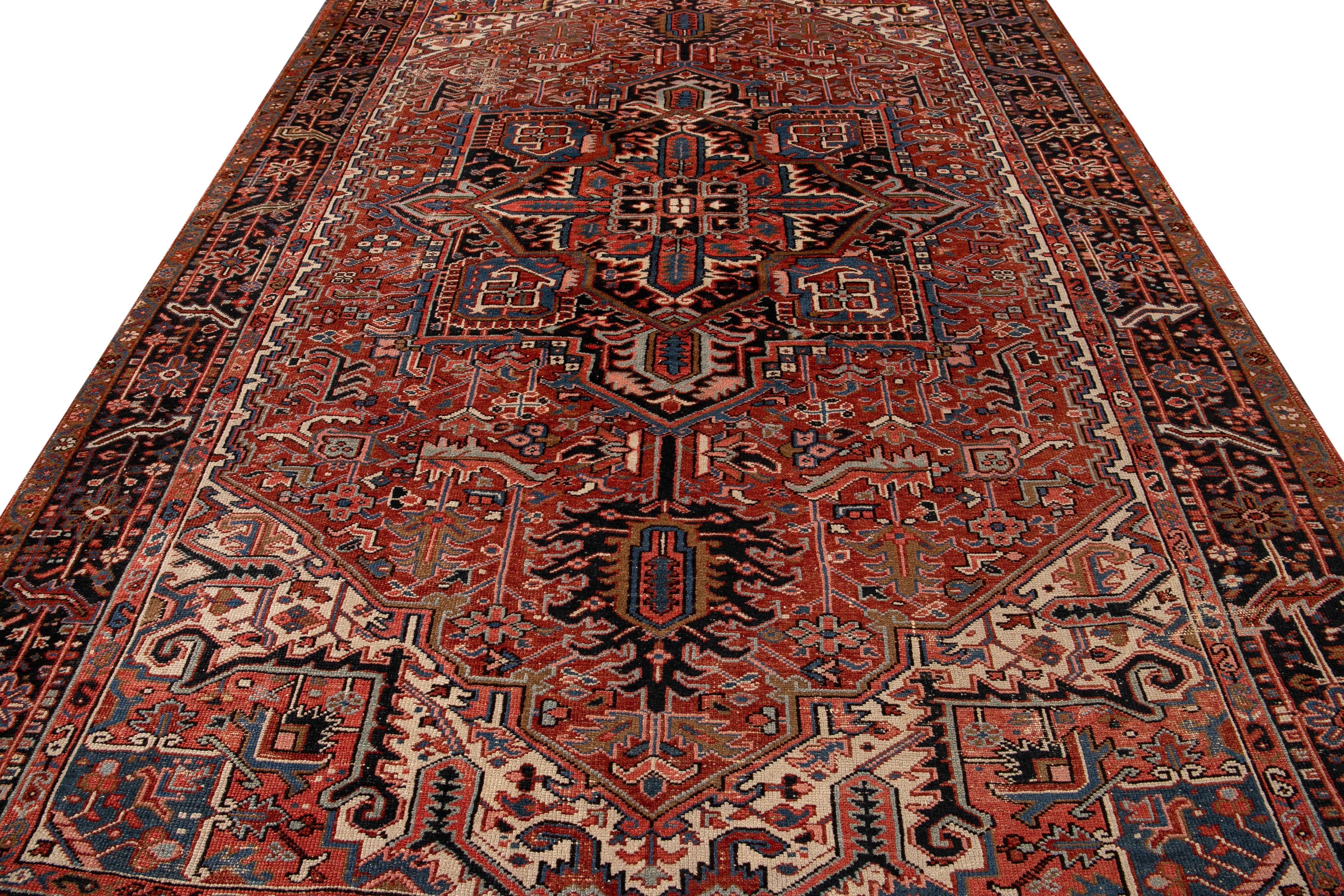 Beautiful antique Persian Heriz hand-knotted wool rug with a rust field. This Heriz rug has a navy-blue frame and multi-color accents in an all-over gorgeous geometric medallion floral design.

This rug measures: 7'11 x 11'10